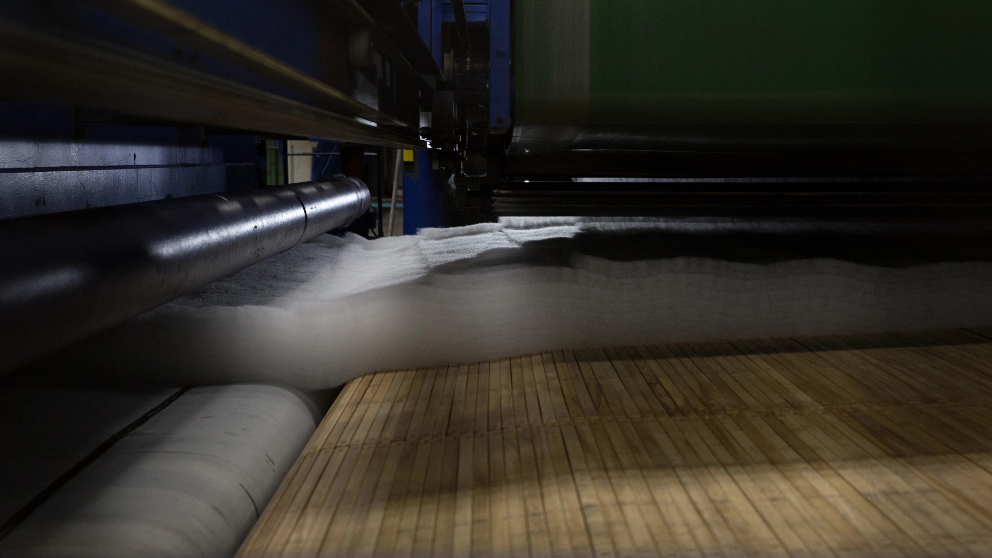 PET felt sheets being compressed and bound by needle-punching machine during the felting process