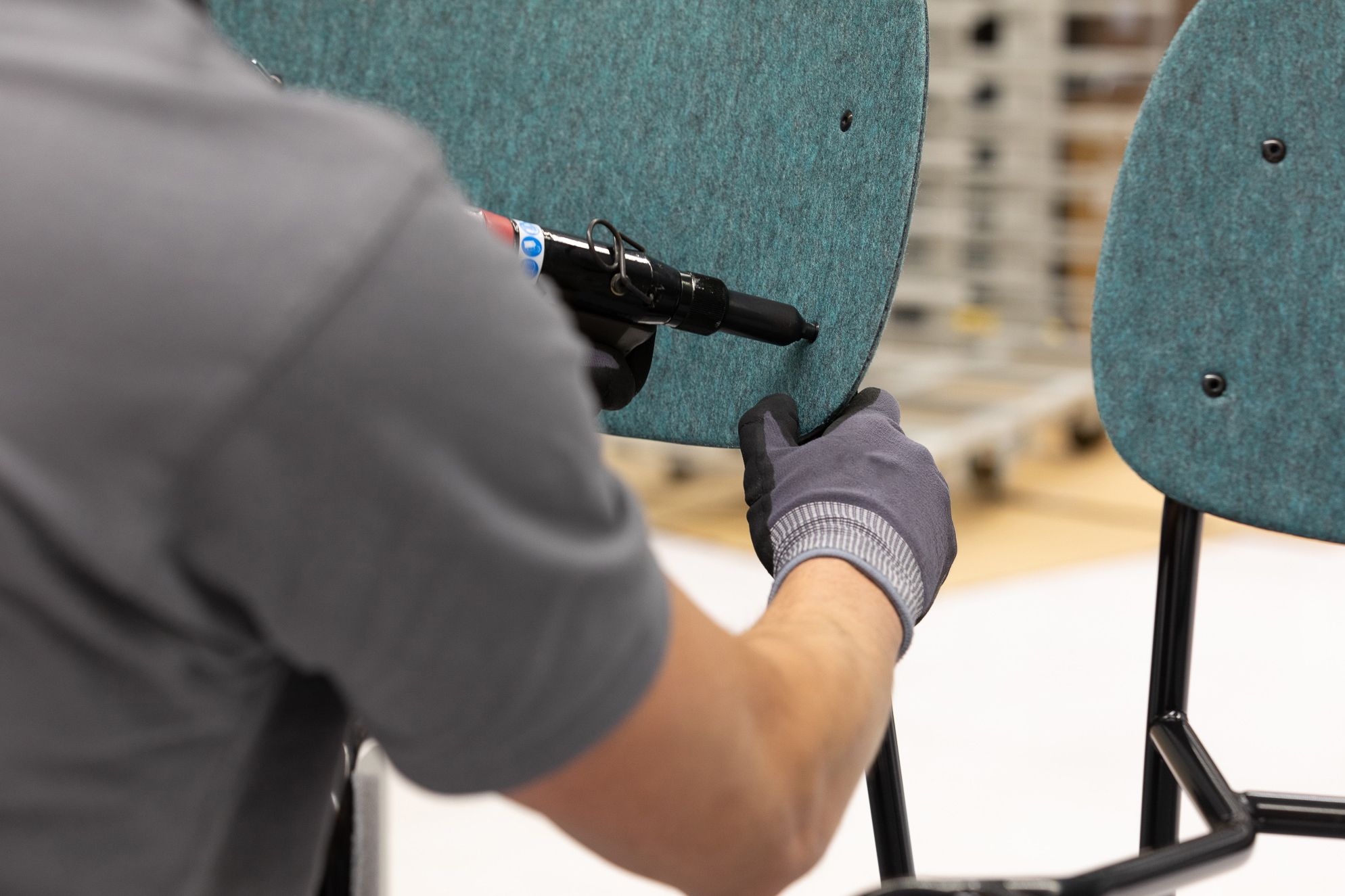 De Vorm production specialist assembling a Hale PET felt backrest onto a chair frame in the factory