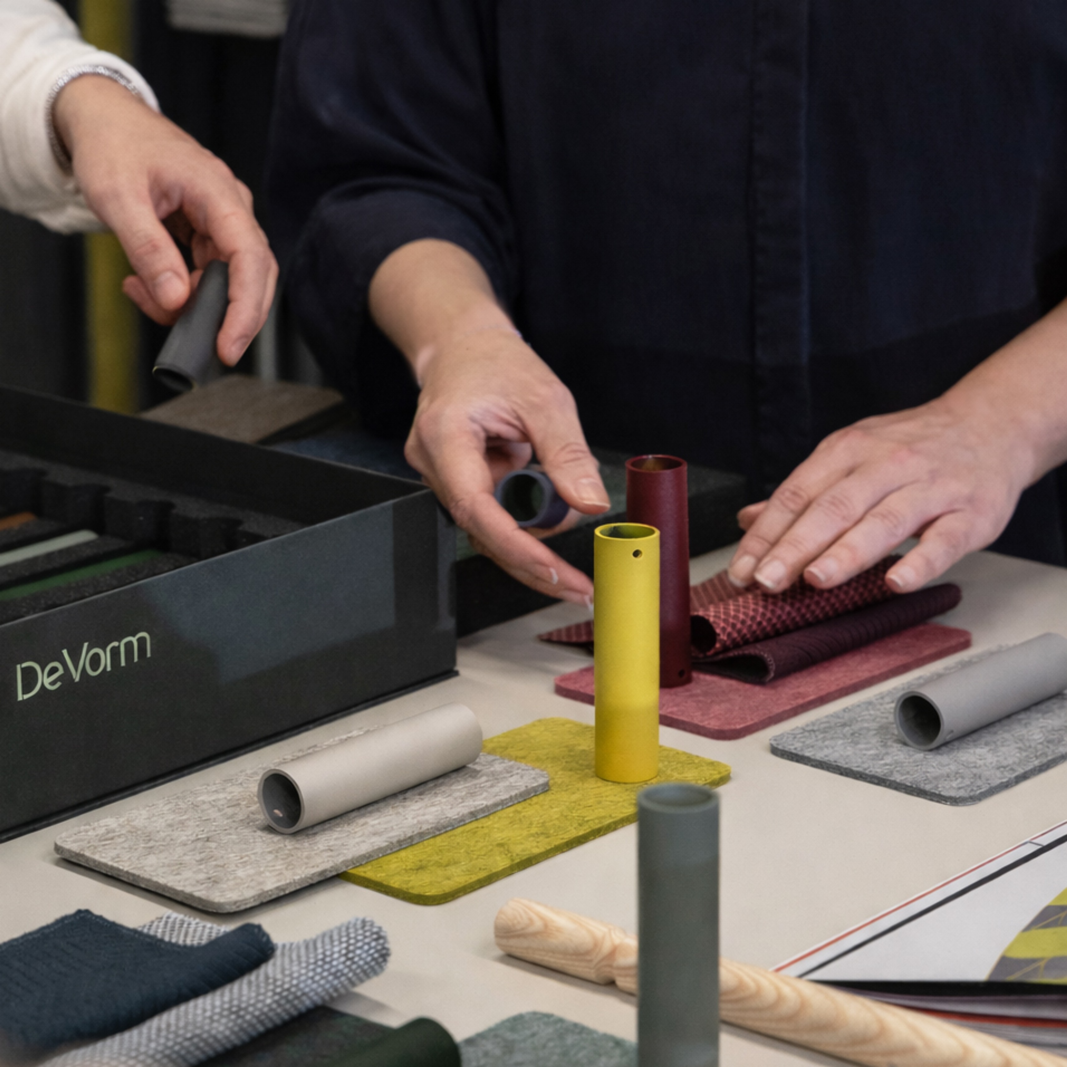 De Vorm team arranging PET felt and material samples with frame colour swatches on a studio table