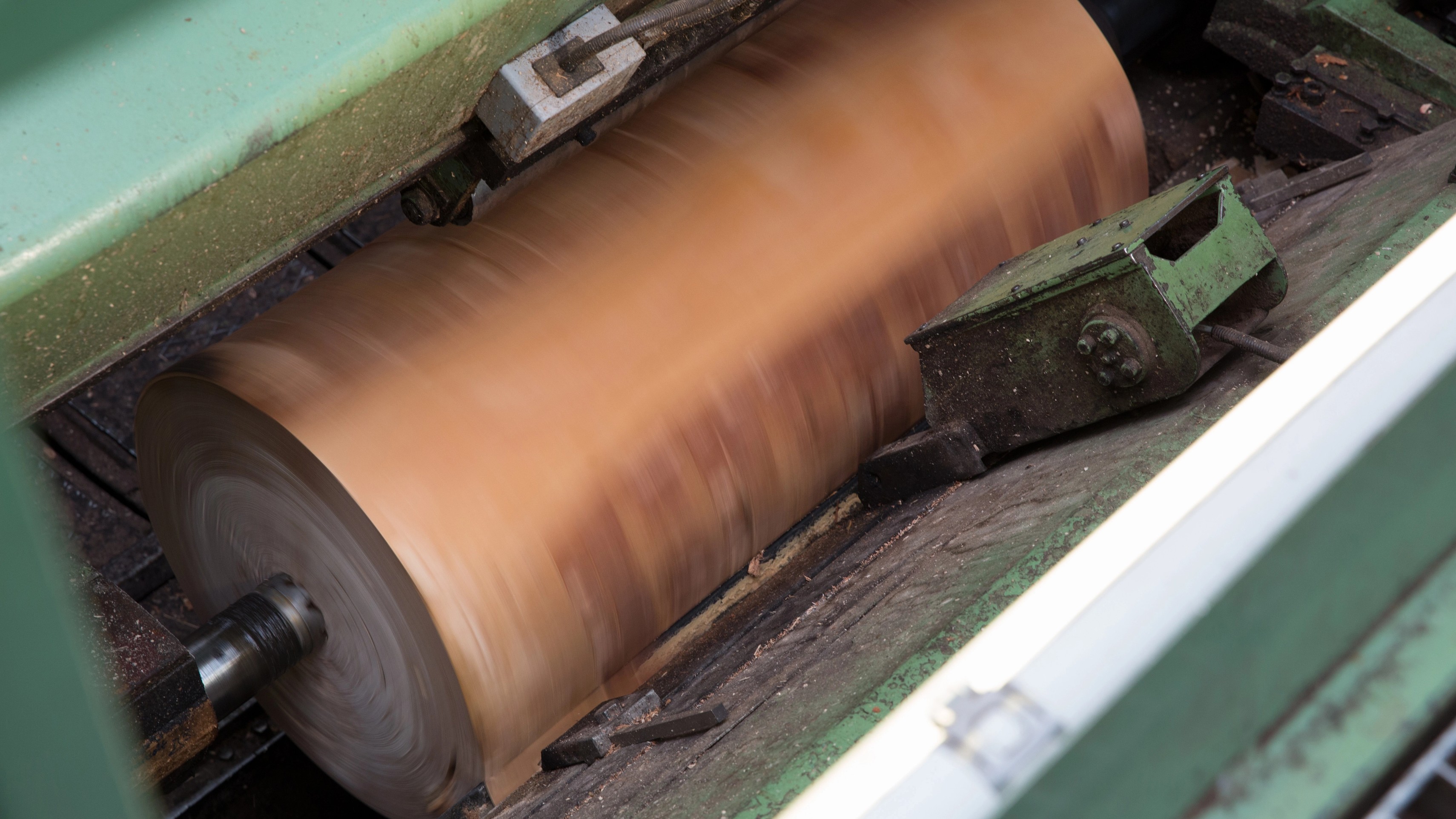 Wood veneer being processed on a rotating lathe during precision woodworking production