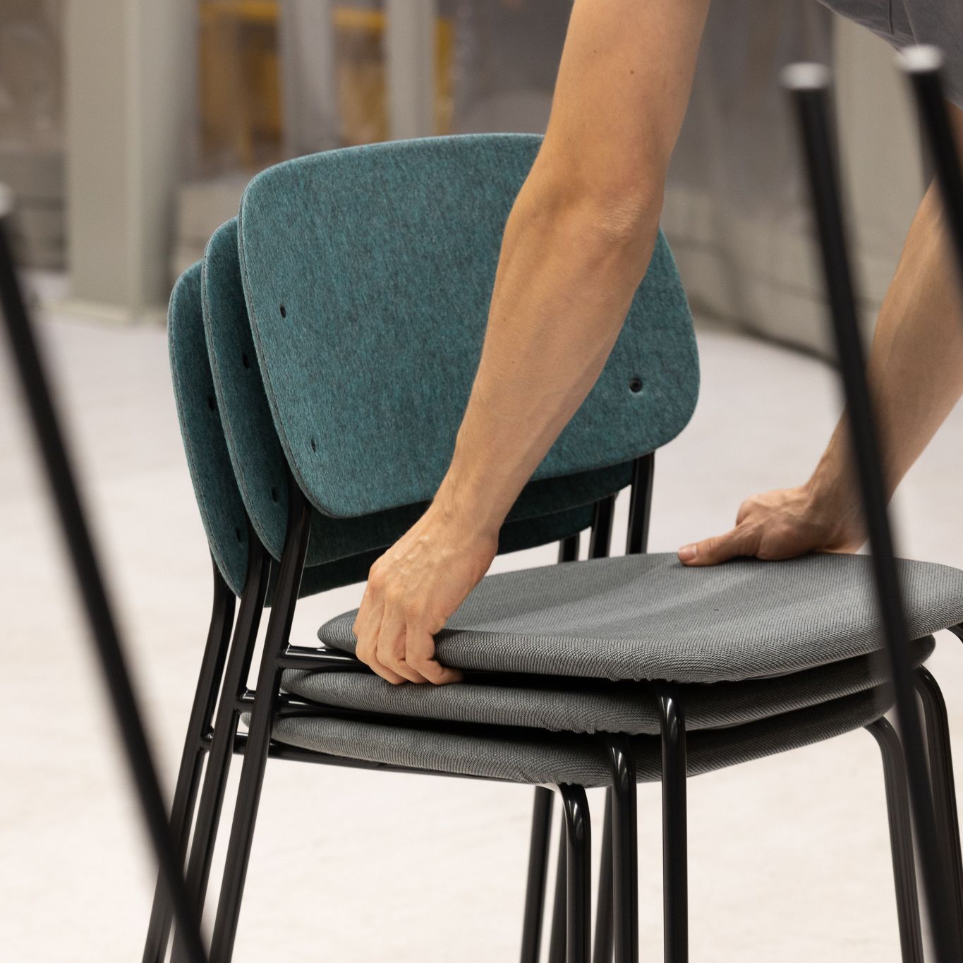 Hale PET Felt Stack Chair being stacked by hand, showing ease of stacking 