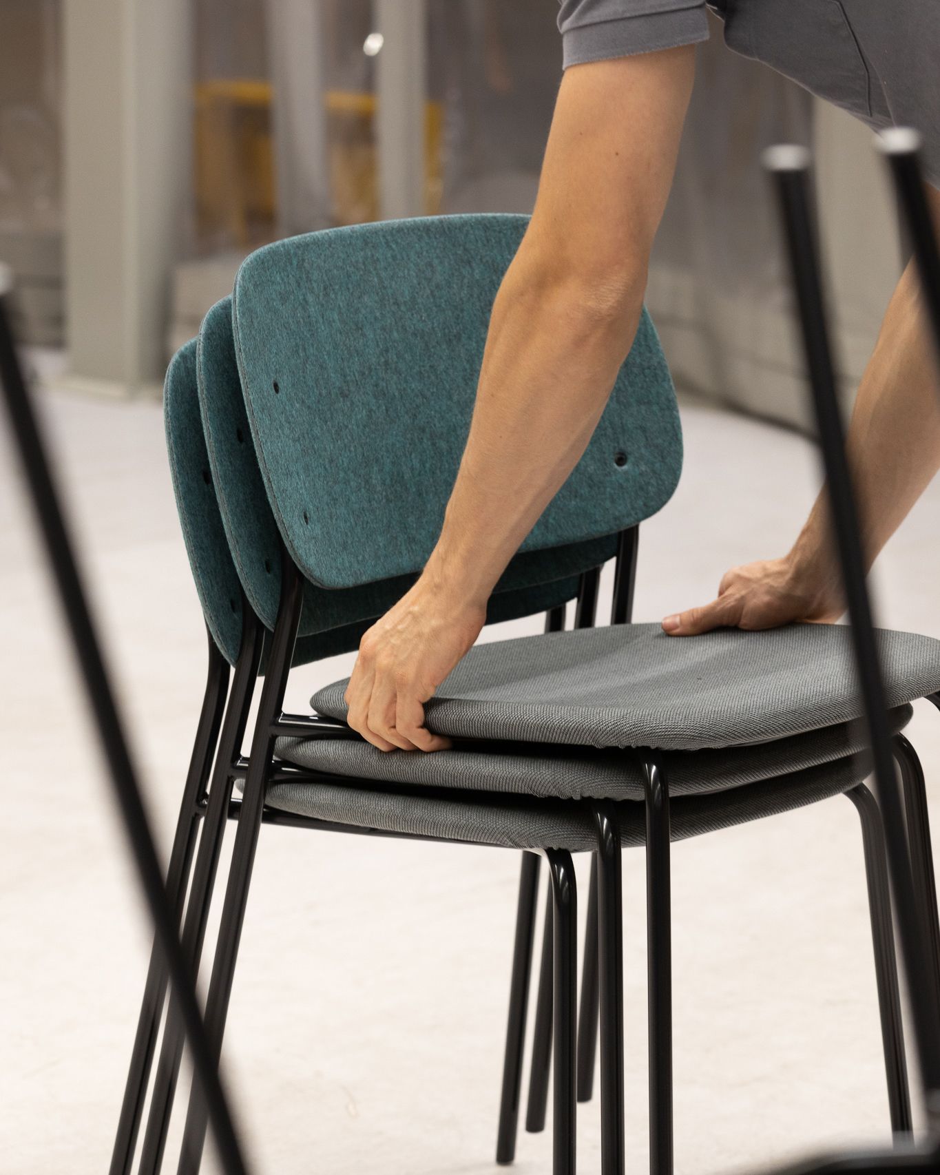 Hale PET Felt Stack Chair being stacked by hand