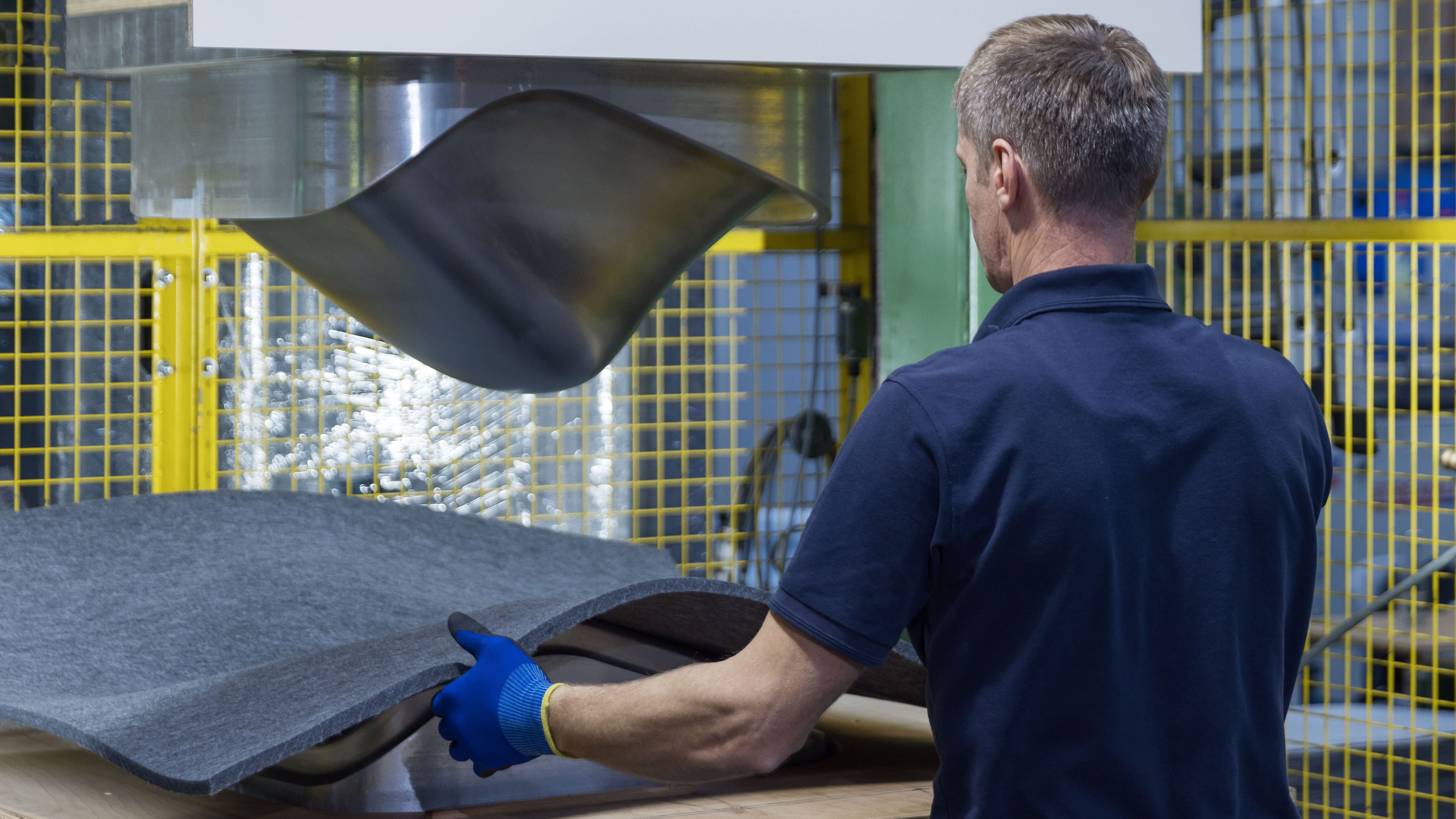 De Vorm production specialist placing a PET felt sheet into a moulding press to form a three-dimensional chair seat