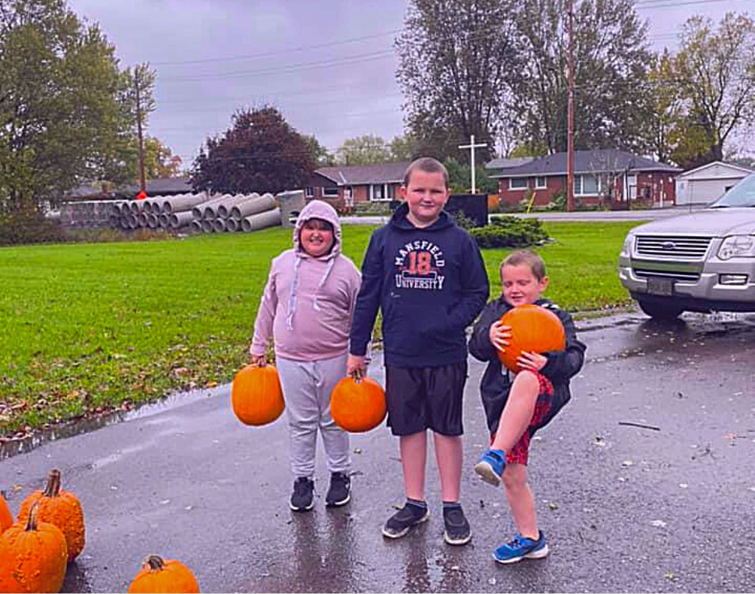 Three kids holding pumpkins they received from the church.