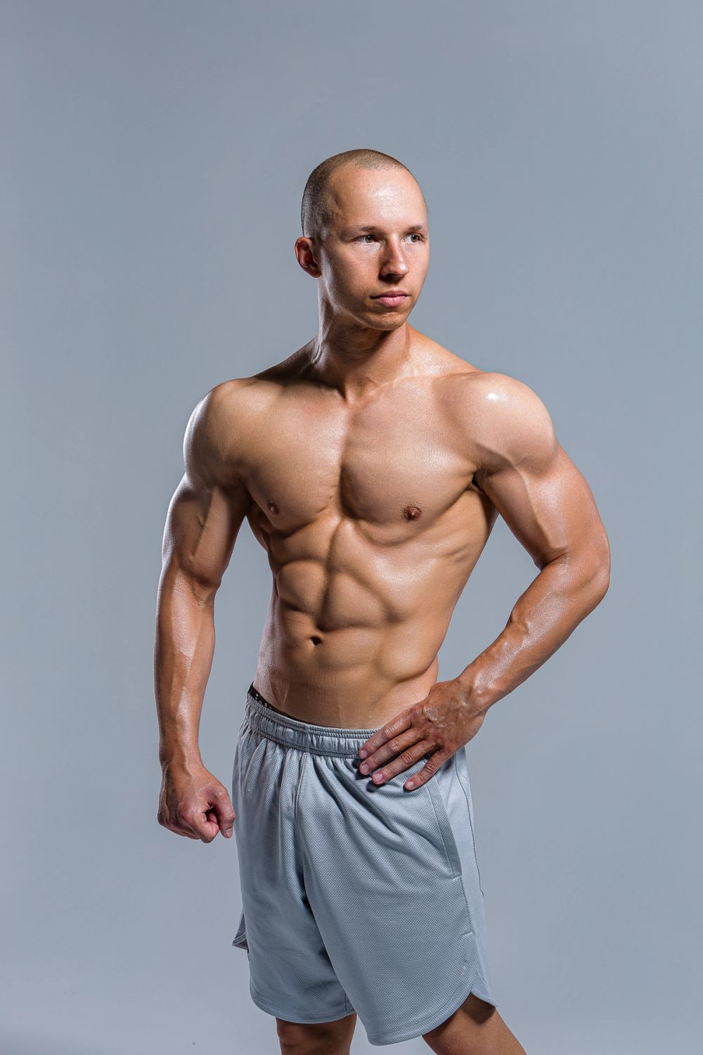 Studio fitness portret muškarca sa naglašenom mišićnom definicijom, snimljen na neutralnoj pozadini, uz kontrolisano studijsko osvetljenje i fokus na formu, proporcije i snagu tela.