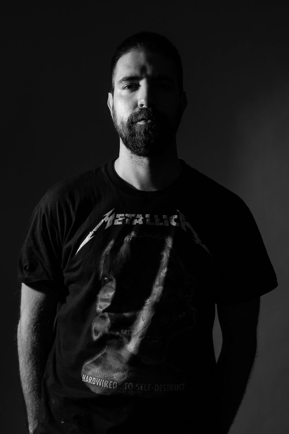 Crno-beli portret muškarca sa naglašenim kontrastom svetla i senke, fokusiran na izraz lica, teksturu i minimalističku kompoziciju.