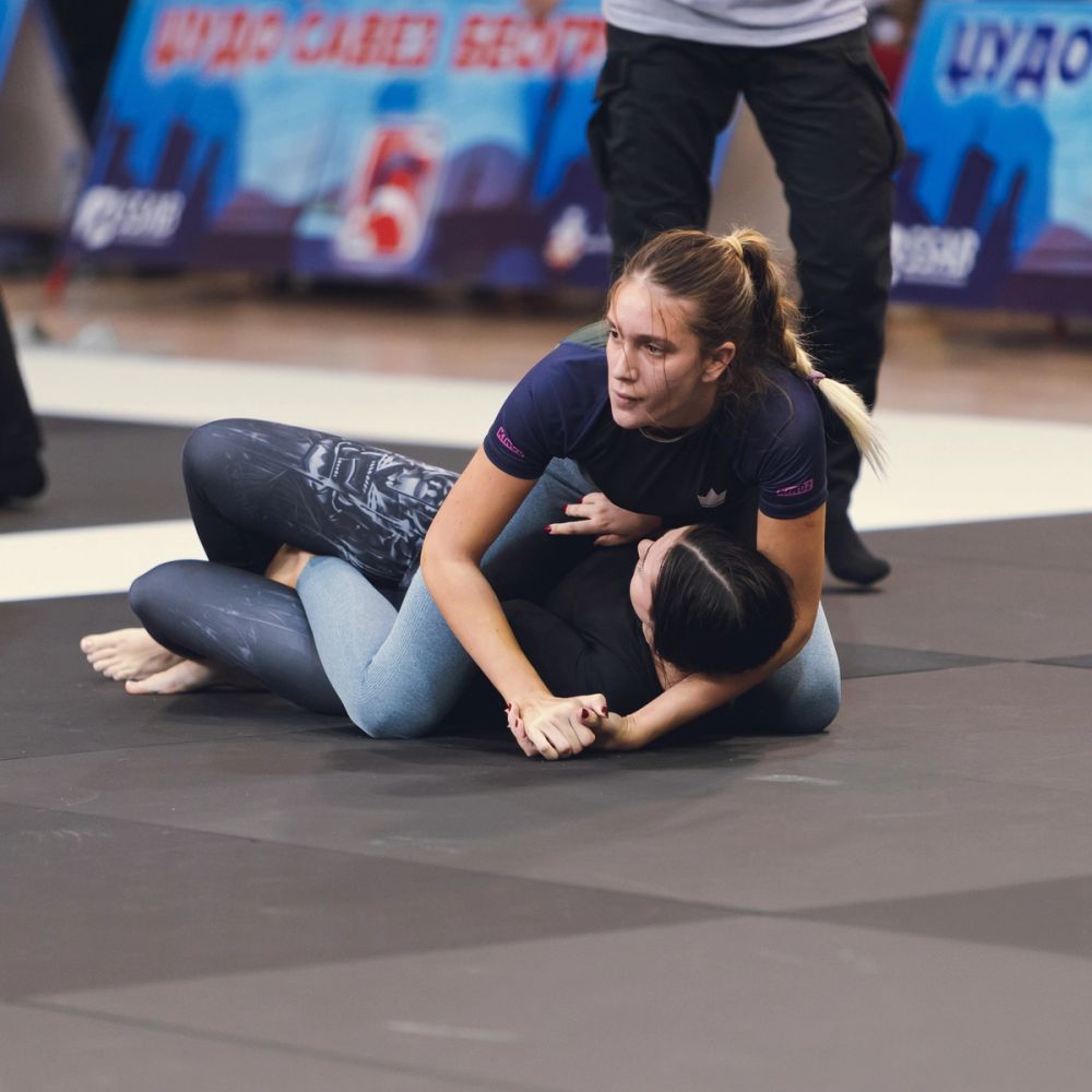 Brazilian jiu-jitsu borba u parteru tokom takmičenja, dve takmičarke u kontrolnoj poziciji na strunjači