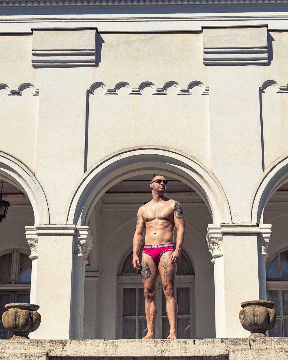 Muški model u slipovima ispred arhitektonskog objekta, profesionalna underwear fotografija muškog donjeg veša u urbanom okruženju