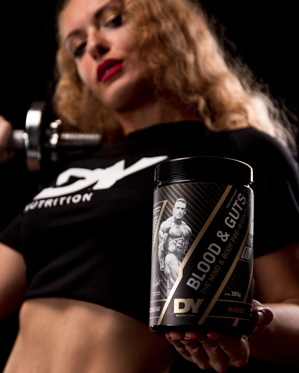 Produkt fotografija fitness suplementa snimljena u studijskim uslovima, sa modelom u pozadini i fokusom na proizvod u prvom planu, uz kontrolisano osvetljenje i tamnu pozadinu.