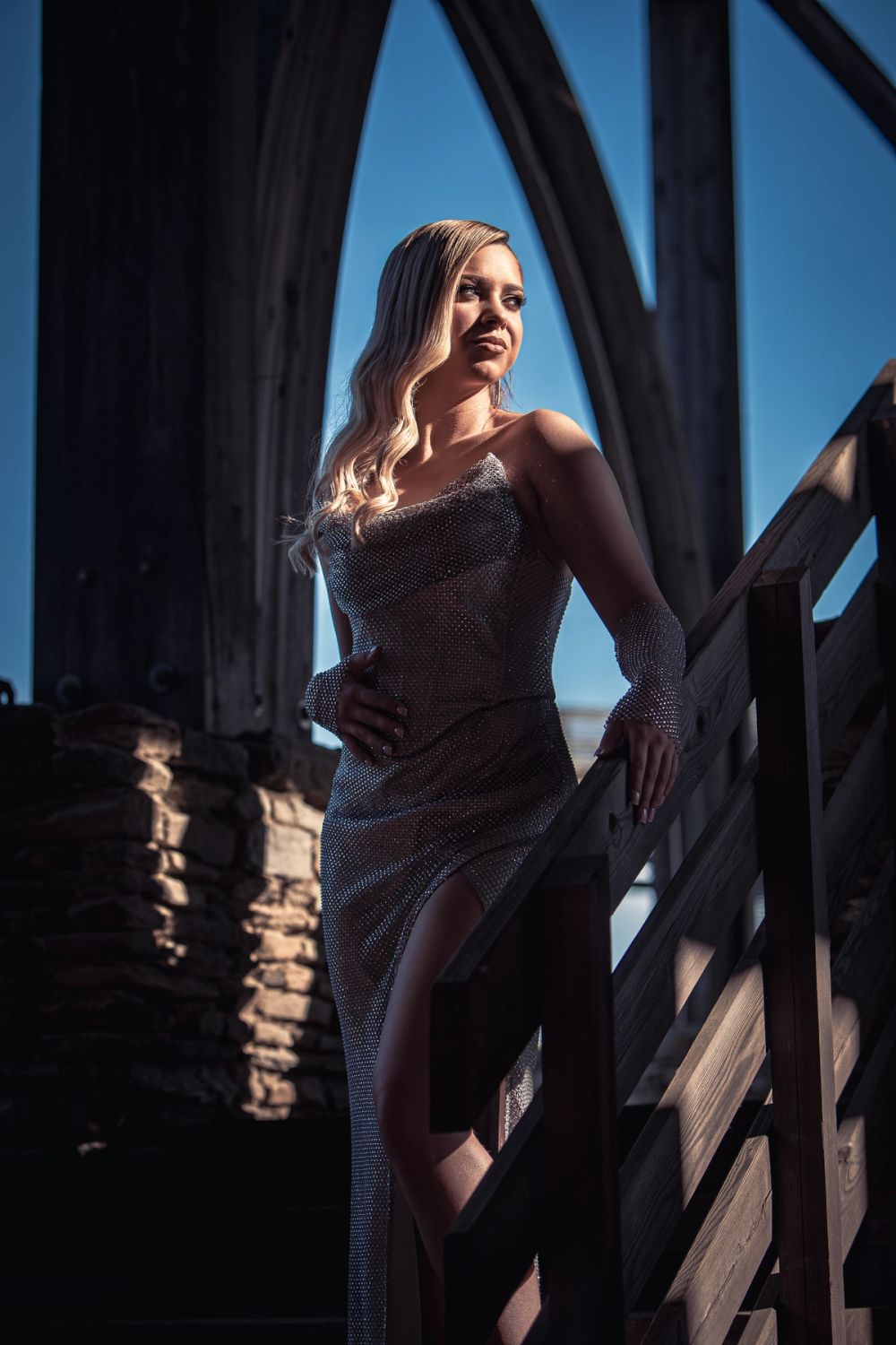 Portret žene u elegantnoj haljini, fotografisan u arhitektonskom ambijentu sa prirodnim svetlom, naglaskom na linije prostora, držanje tela i izražajnu atmosferu.