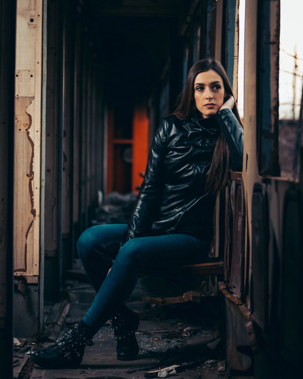 Portret žene u industrijskom, napuštenom ambijentu, sa naglaskom na atmosferu prostora, kontrast svetla i senke i izražajan, zamišljen pogled.