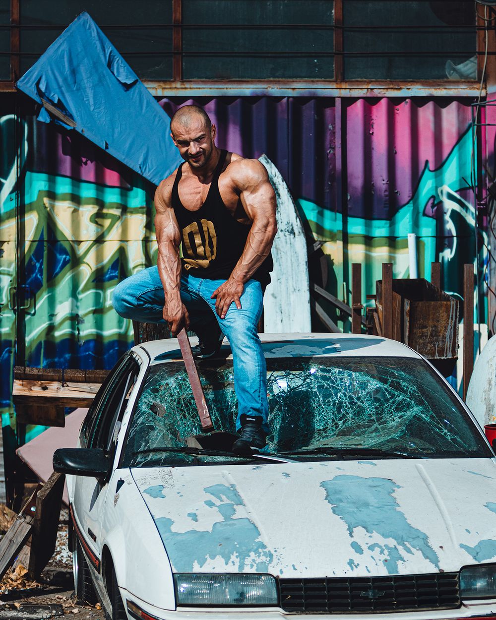 Urban fitness portret muškarca u industrijskom okruženju, snimljen u dinamičnoj sceni sa naglašenom fizičkom snagom, dramatičnim kontrastnim osvetljenjem i fokusom na sirovu energiju i intenzitet.