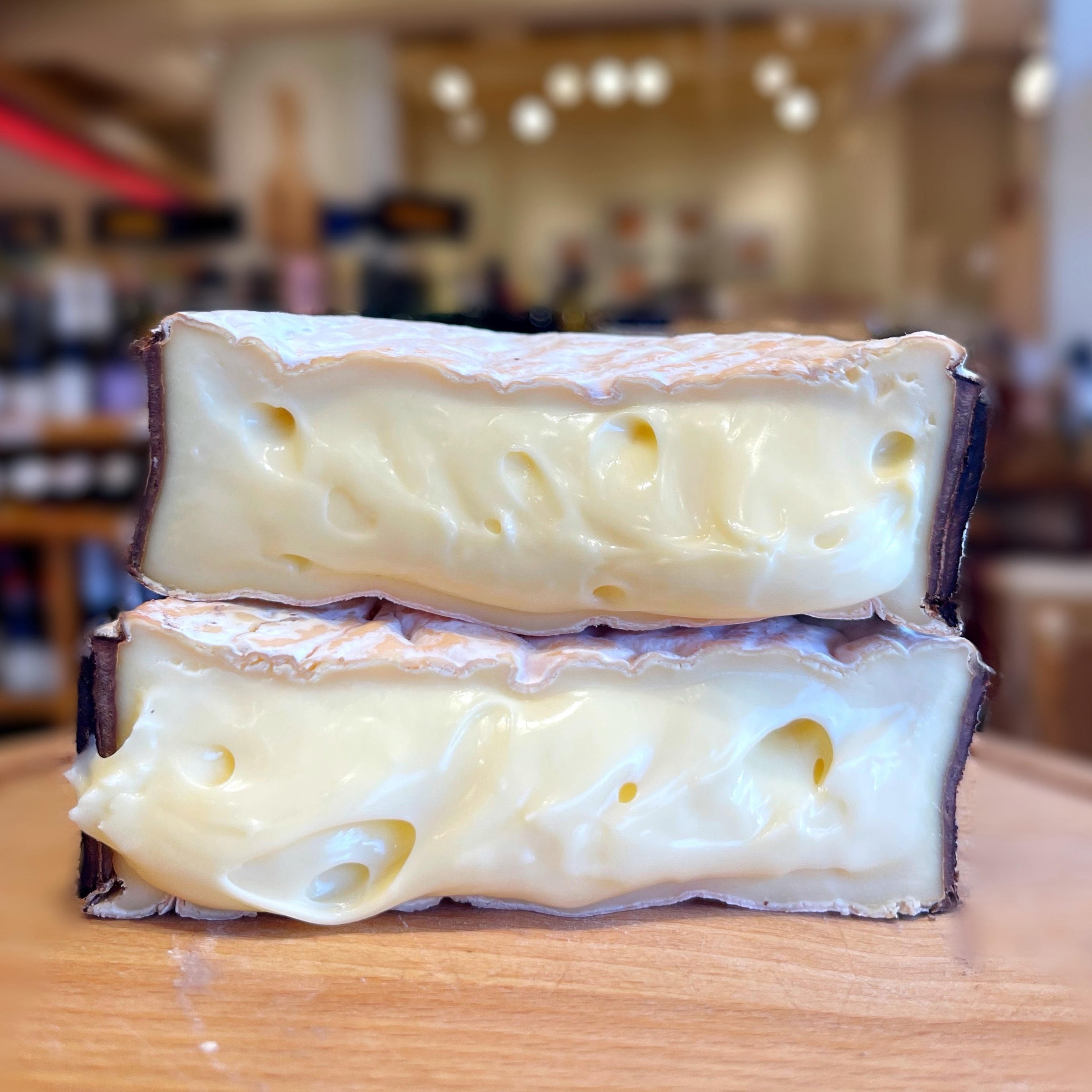 Two halves of a cut Rush Creek Reserve stacked to show the soft, glossy paste inside the bark band