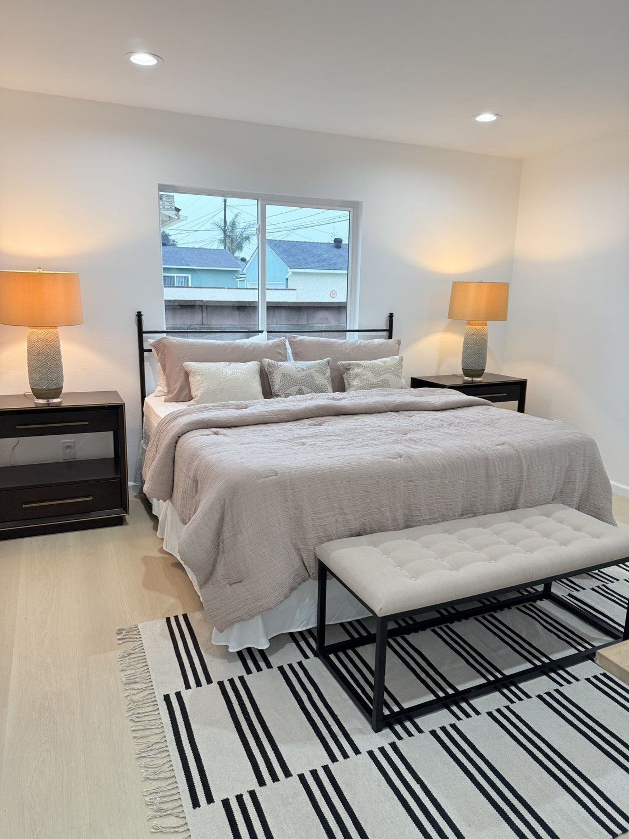Contemporary bedroom with a large bed, nightstands with lamps, and a striped area rug
