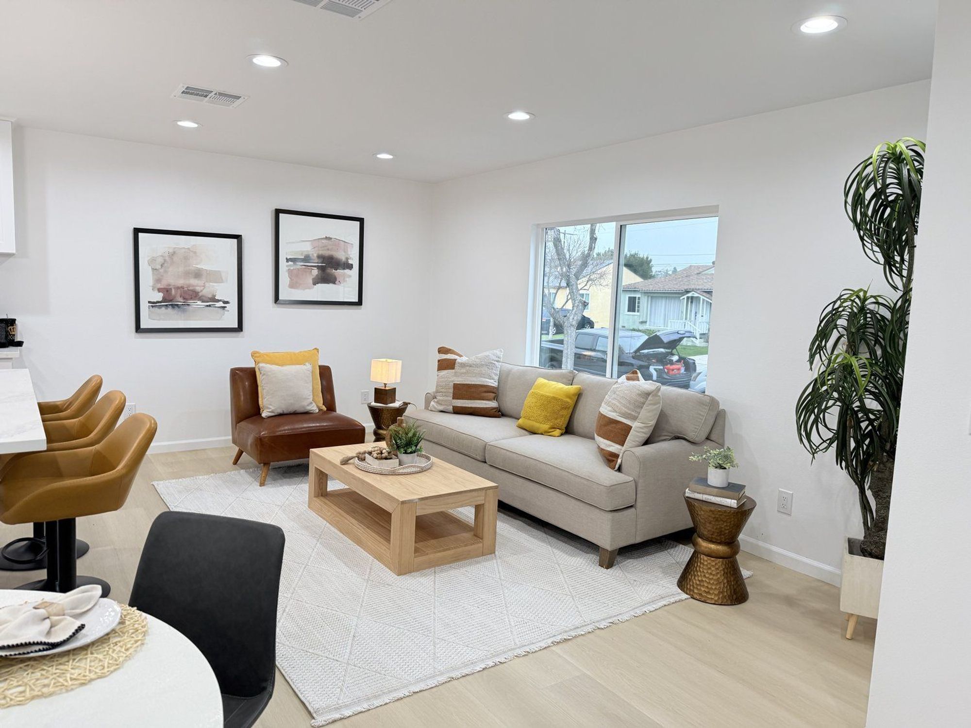 A modern living room with a beige sofa, leather chairs, and abstract art