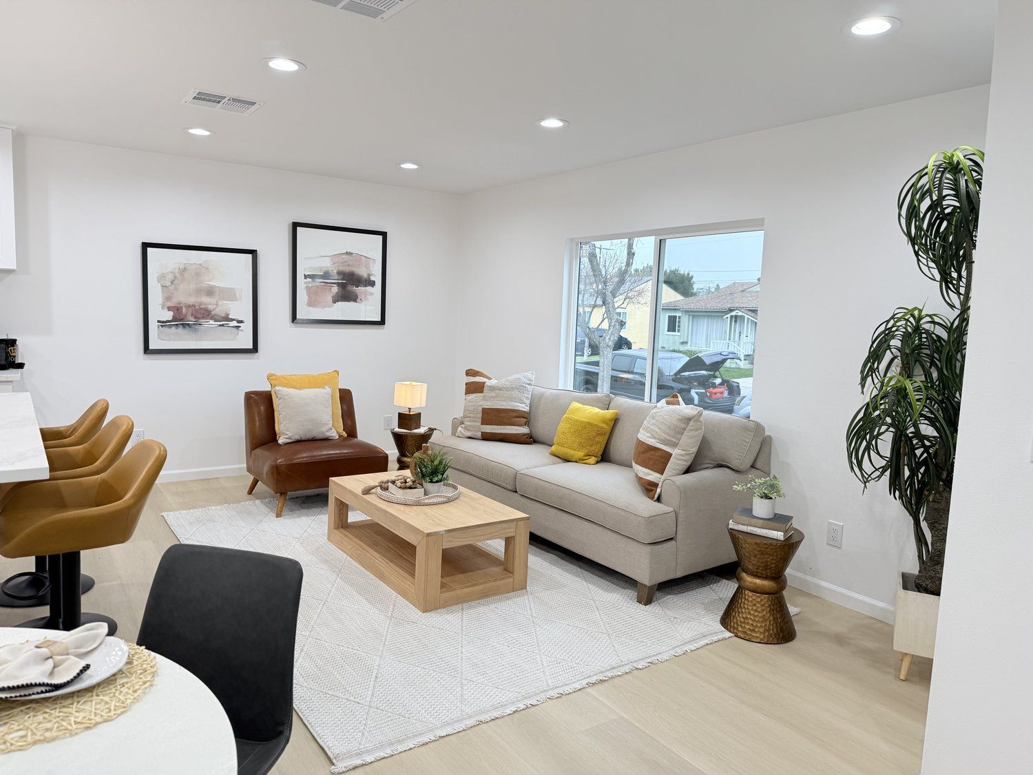 A modern living room with a beige sofa, leather chairs, and abstract art