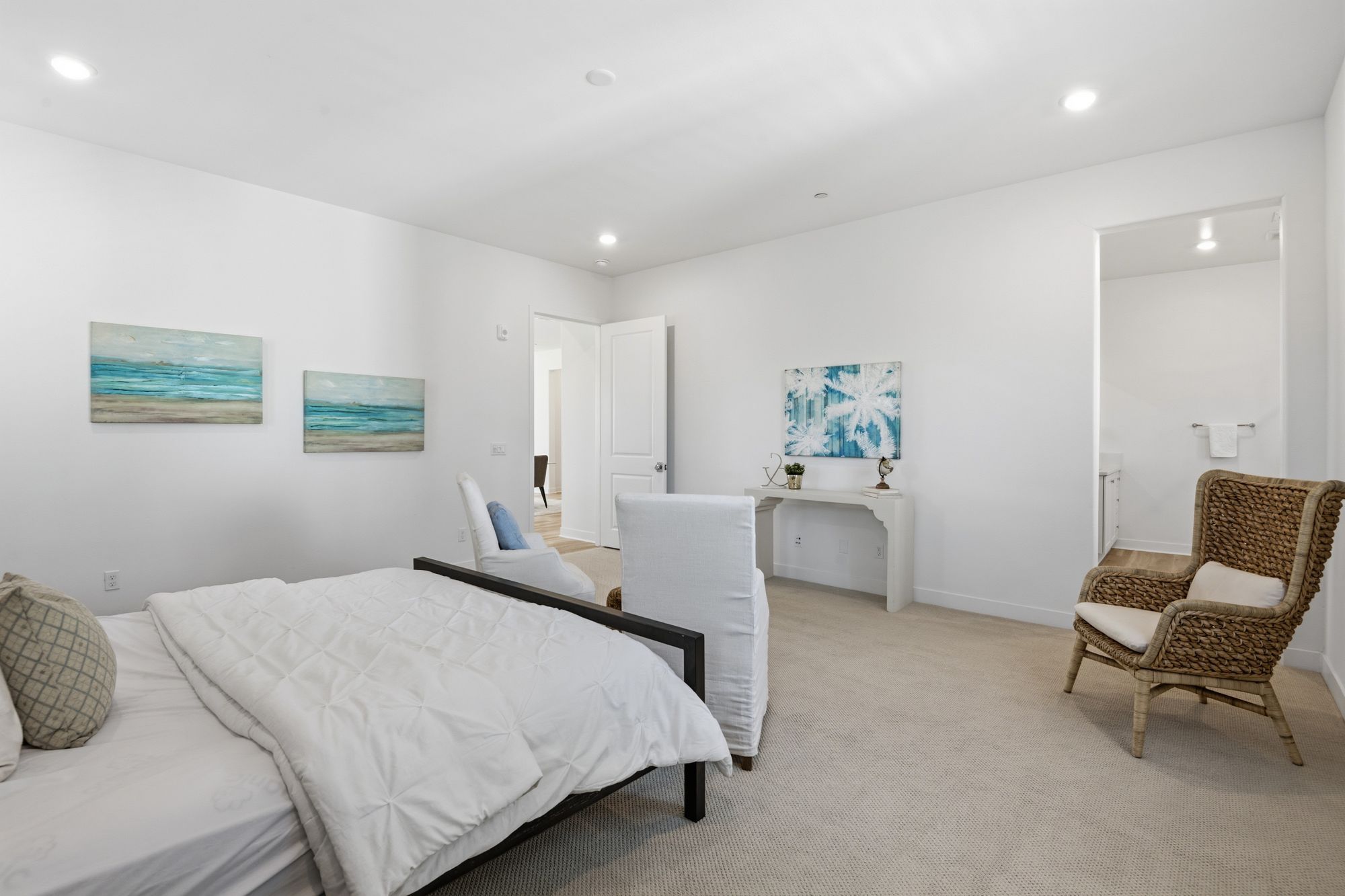 Modern bedroom with soft colors, a made bed, and ocean-themed artwork
