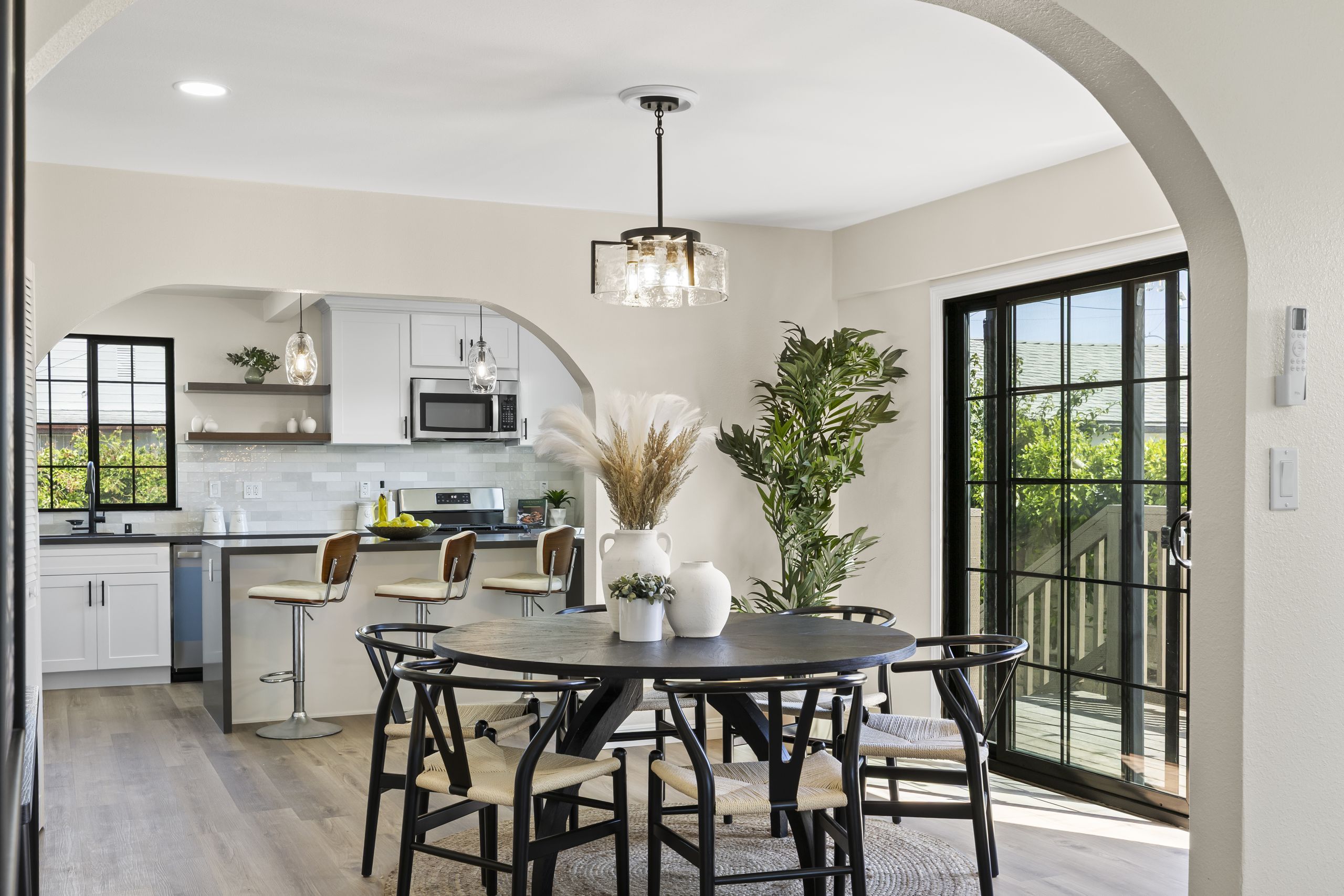 The dining room of the same Santa Ana home, with a round black table and woven chairs opening to the kitchen