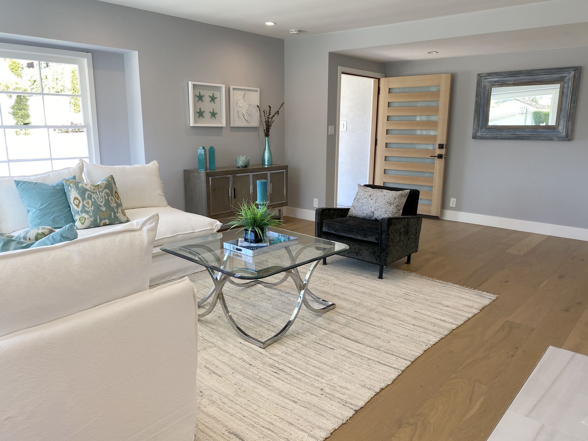 A coastal contemporary living room with neutral furnishings and bright accents