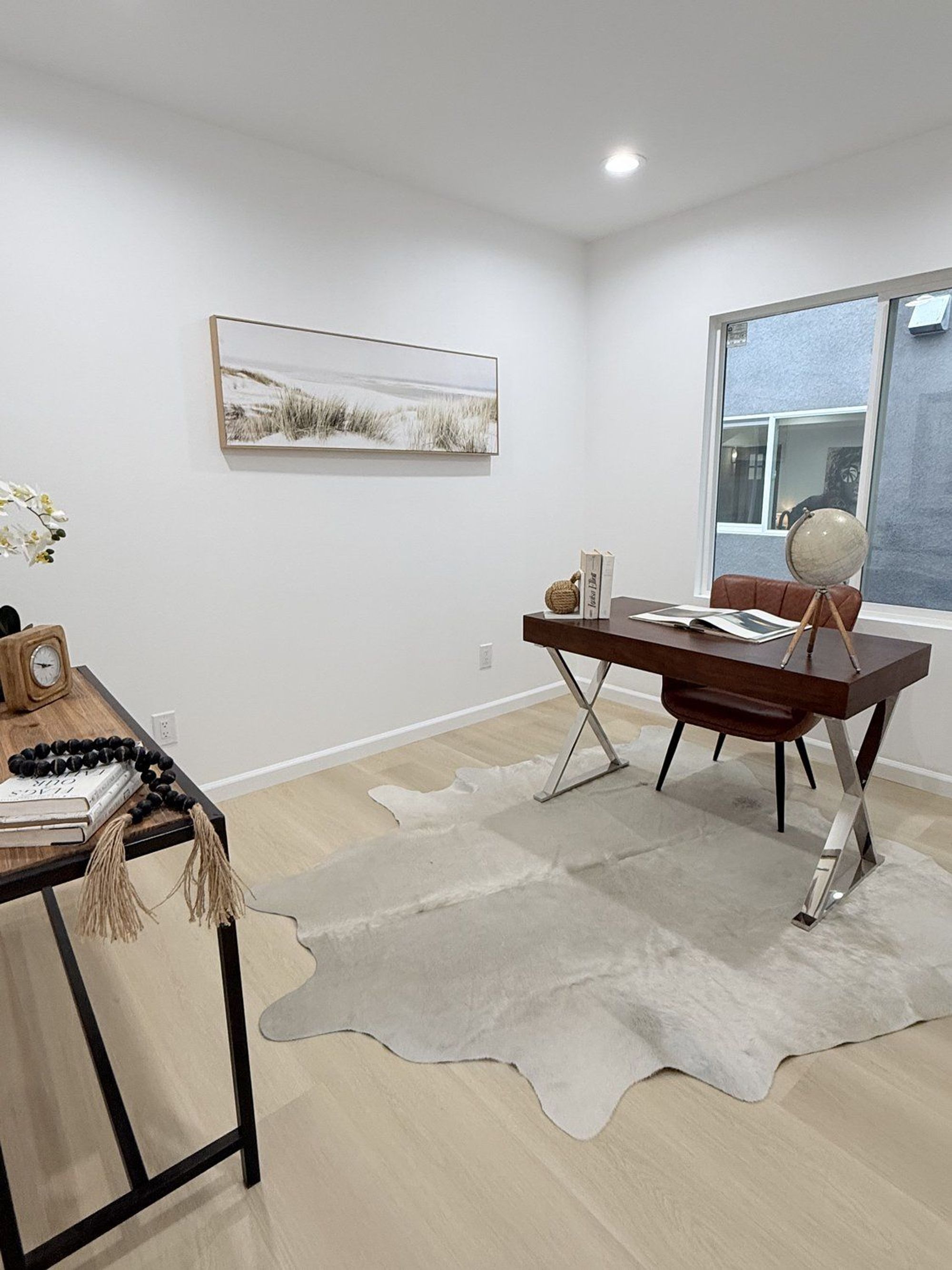 A home office with a wooden desk, a cowhide rug, and contemporary decor
