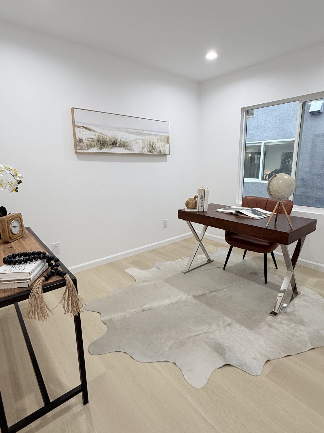 A home office with a wooden desk, a cowhide rug, and contemporary decor