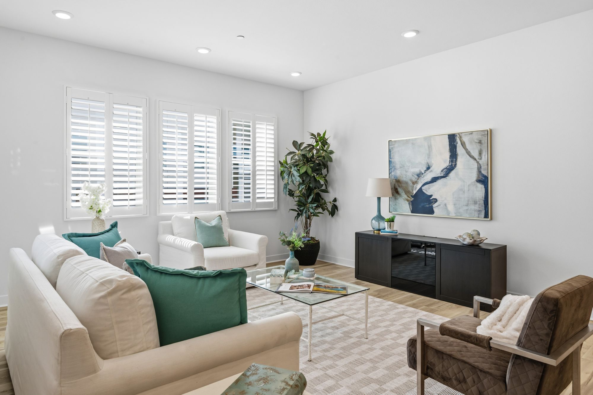 Modern living room with white sofa, turquoise cushions, and abstract wall art