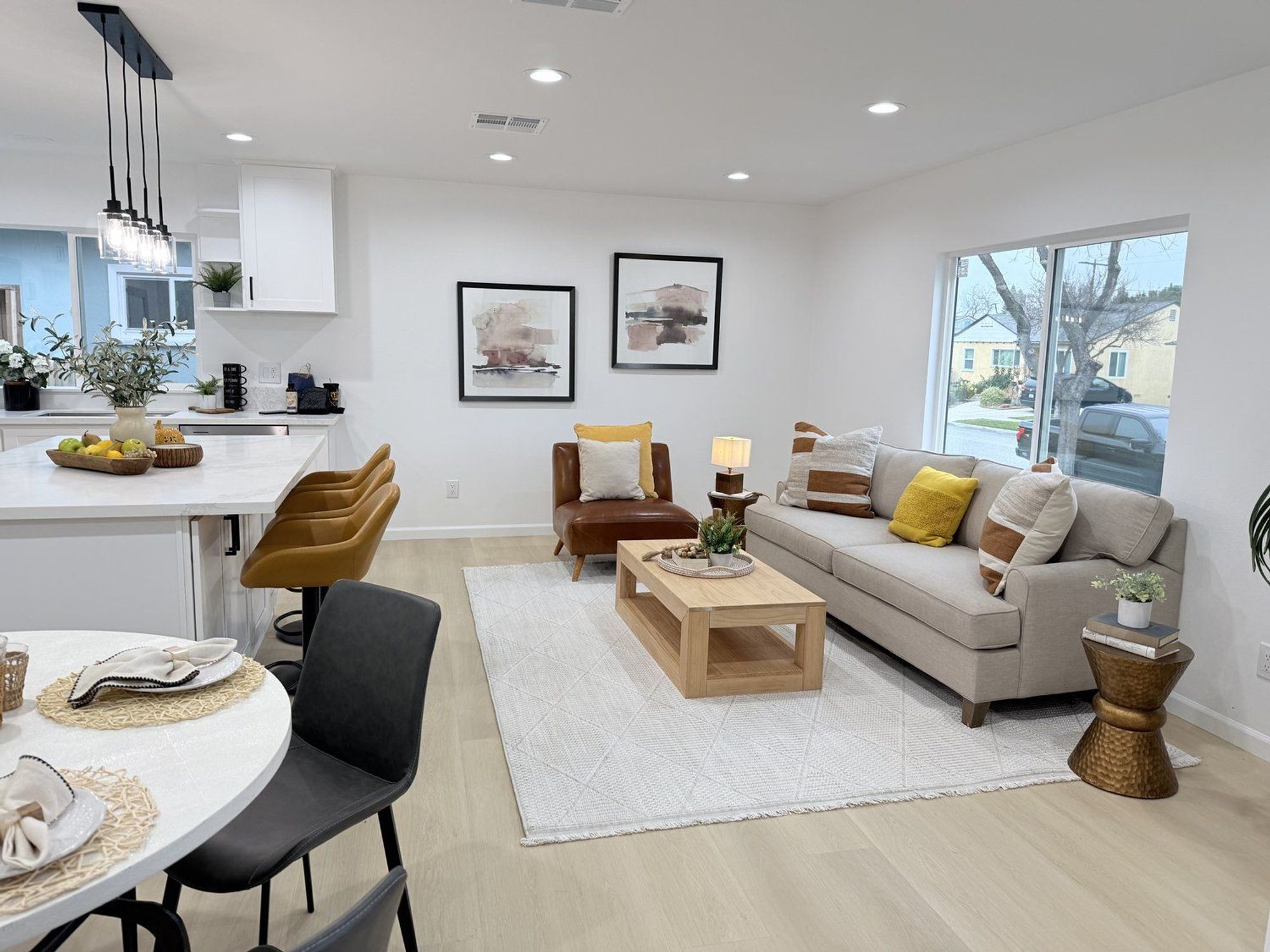 Contemporary living room with a gray sofa, leather chair, wooden coffee table, and round dining table