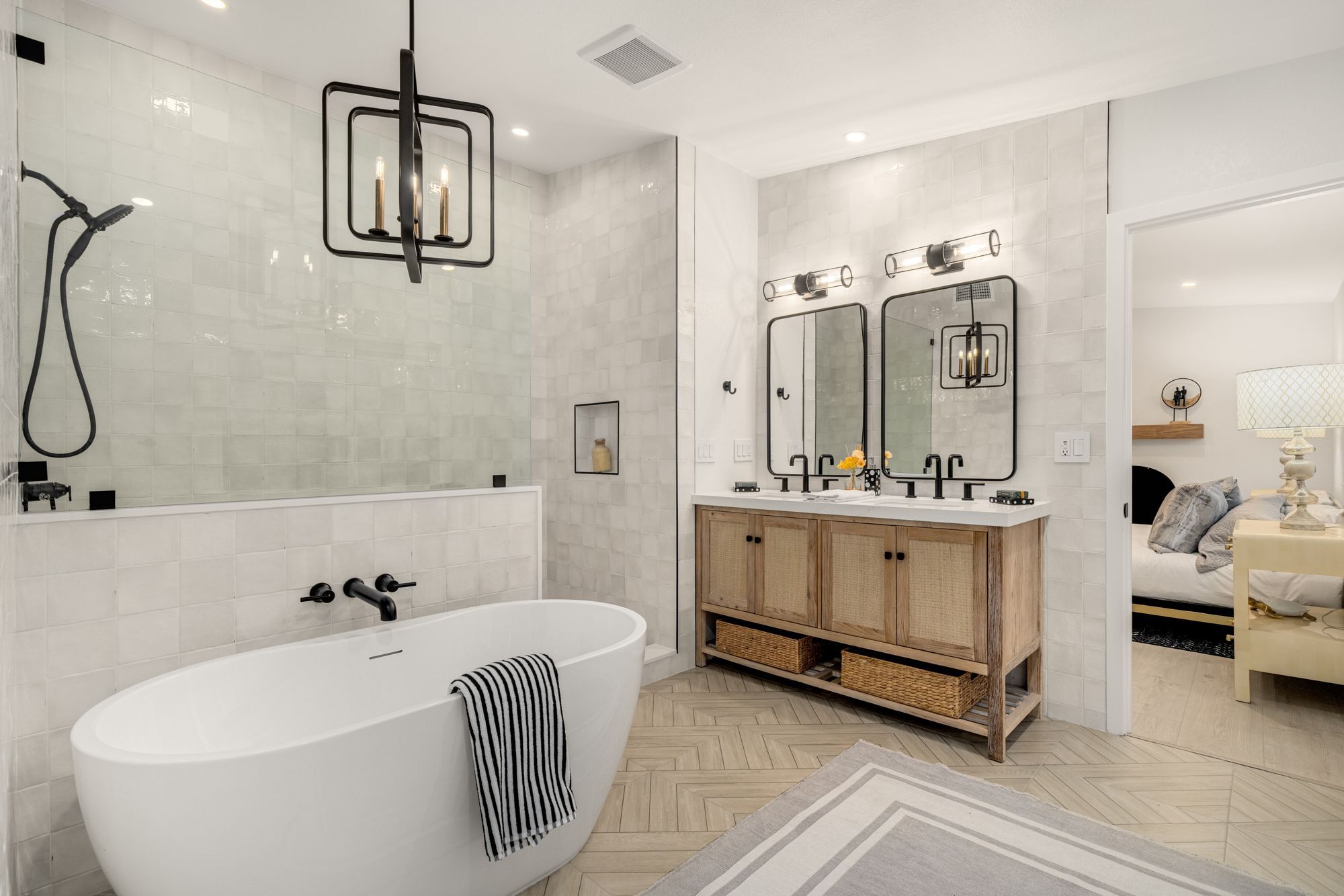 A bathroom with a freestanding tub, dual mirrors, and herringbone floor