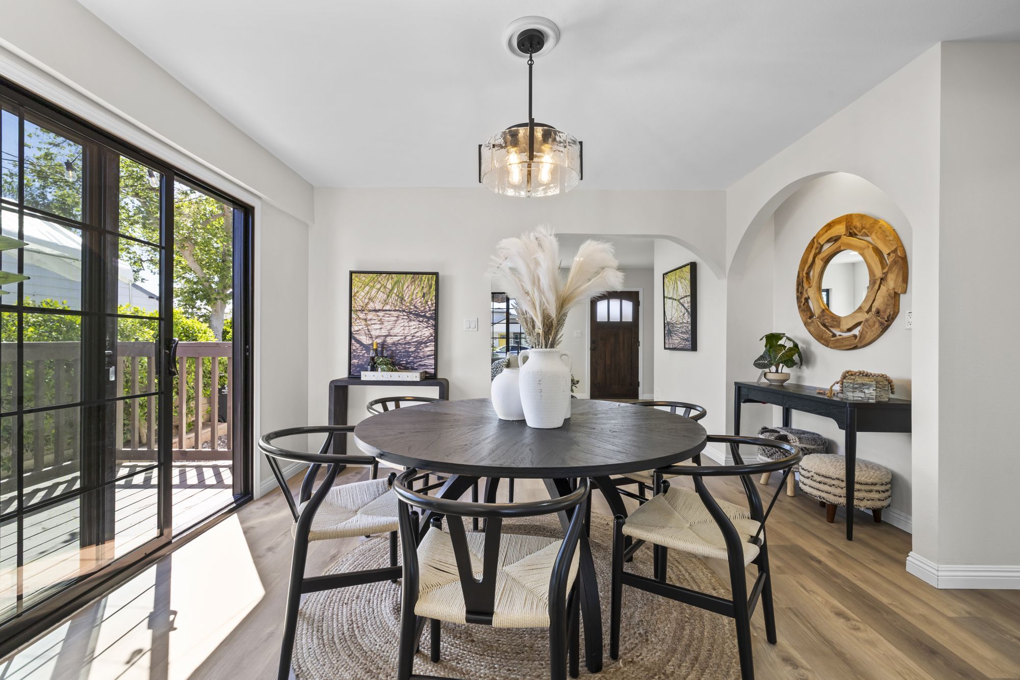 A modern dining area with a round black table, woven chairs, and a pendant light
