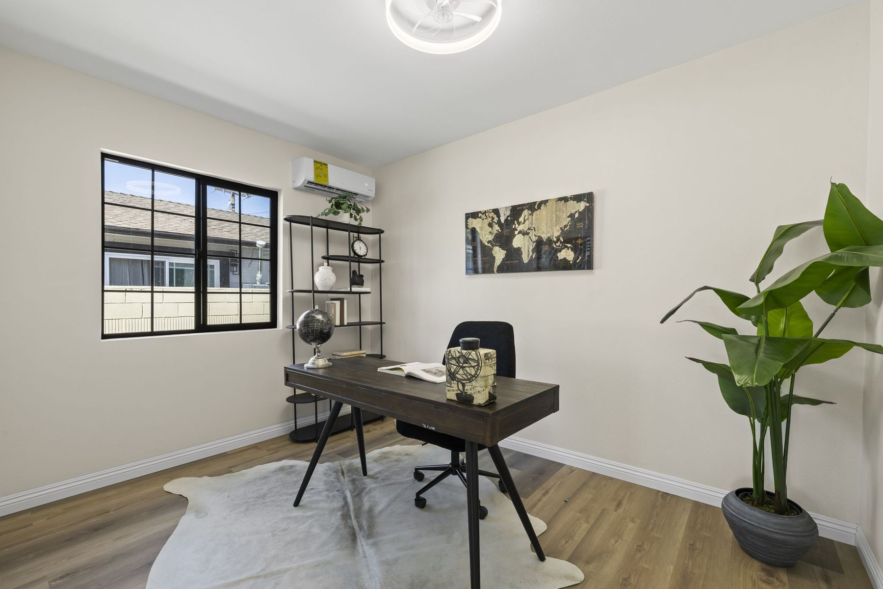 A staged home office in Santa Ana with a wood desk, black chair and plant