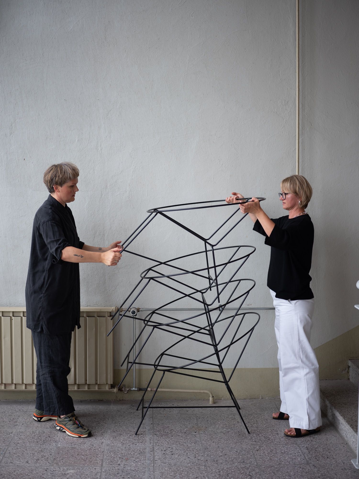 The two founders lifting a stack of bare steel chair frames.