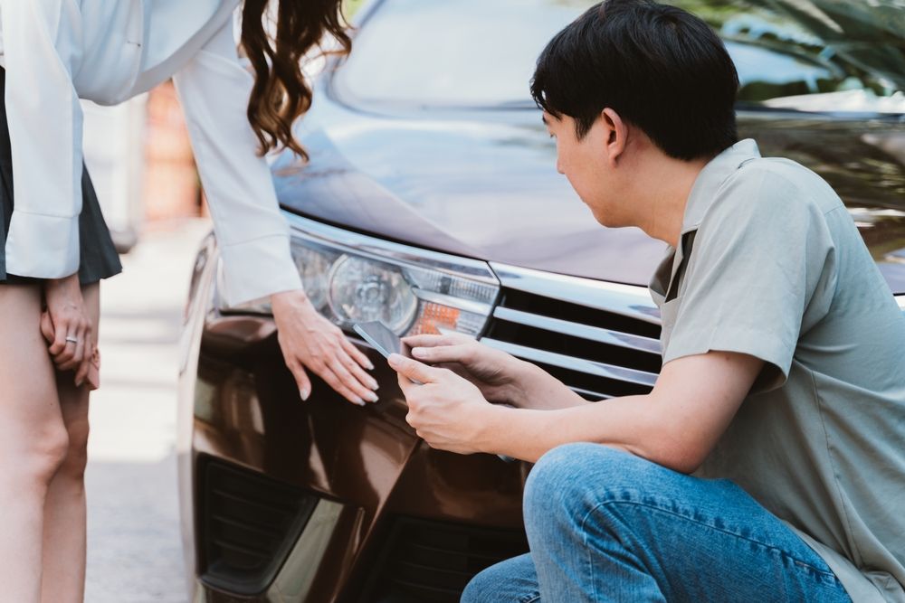 Driver and woman examining vehicle damage after a car accident illustrating how drowsy driving and daylight saving time fatigue can lead to crashes.
