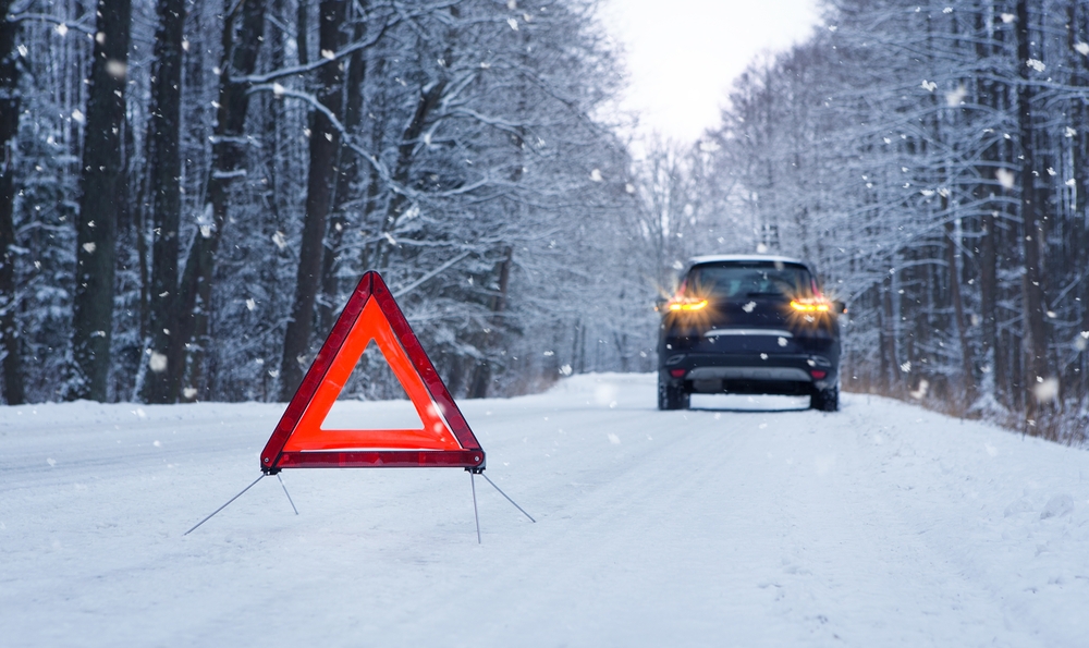 Image Warning triangle on a snowy road with a stopped SUV in the background, showing winter driving hazards in South Jersey.