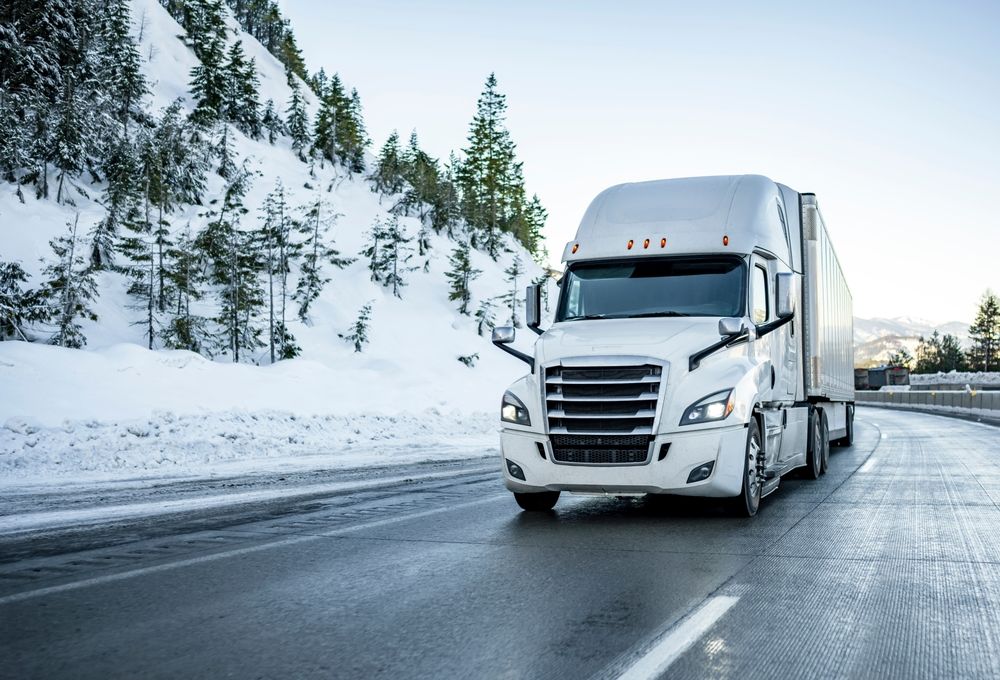 A white tractor-trailer driving on a slick, snow-lined New Jersey highway during hazardous winter conditions.
