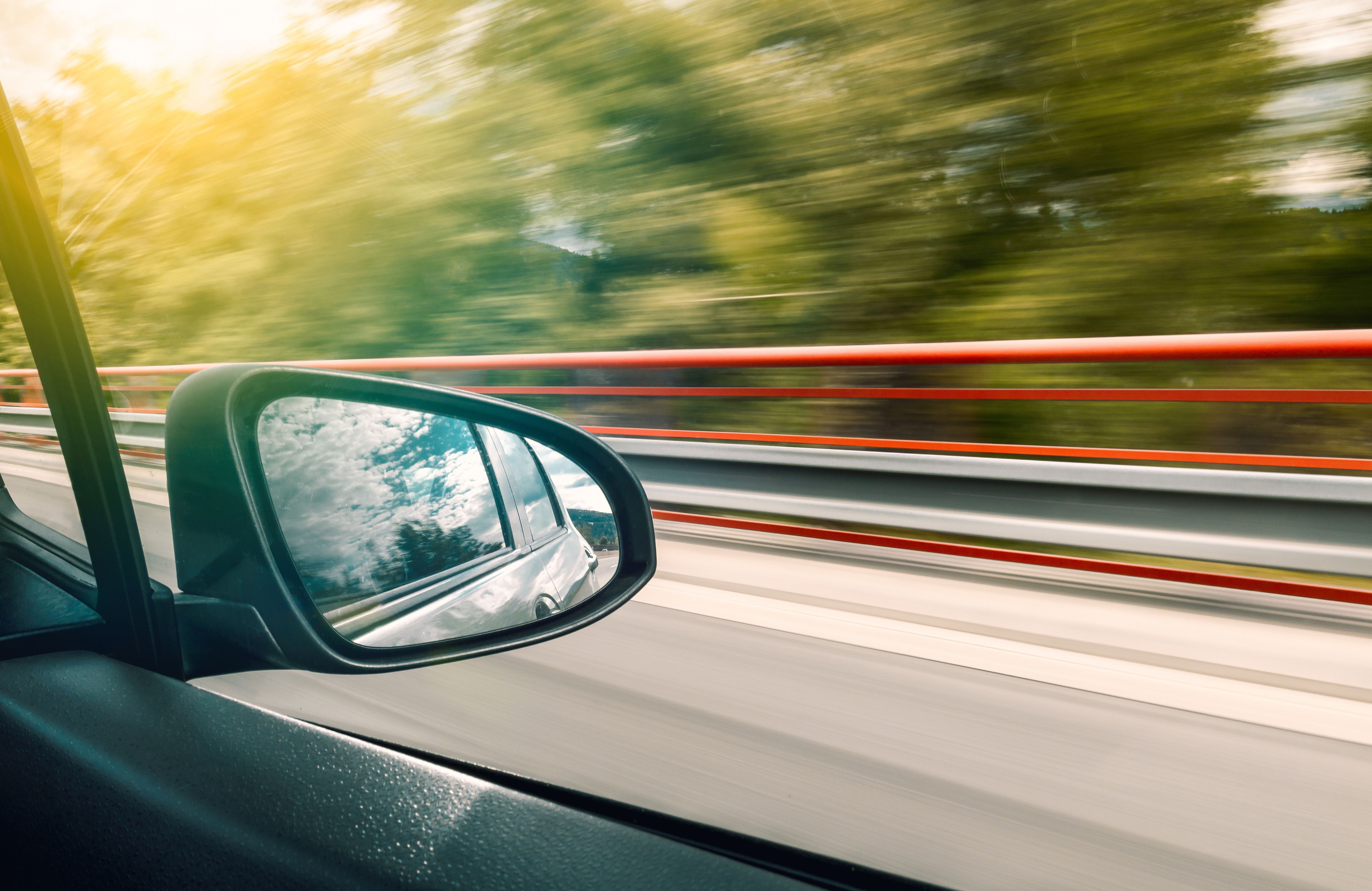 Image Close-up of a car side mirror reflecting traffic while speeding down a New Jersey highway, illustrating the fast-moving and dangerous road conditions that lead to summer car accidents along the Jersey Shore corridor.