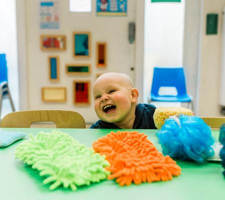 Baby sat at a table laughing
