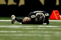 New Orleans Saints quarterback Tyler Shough lies on the field after being tripped up.