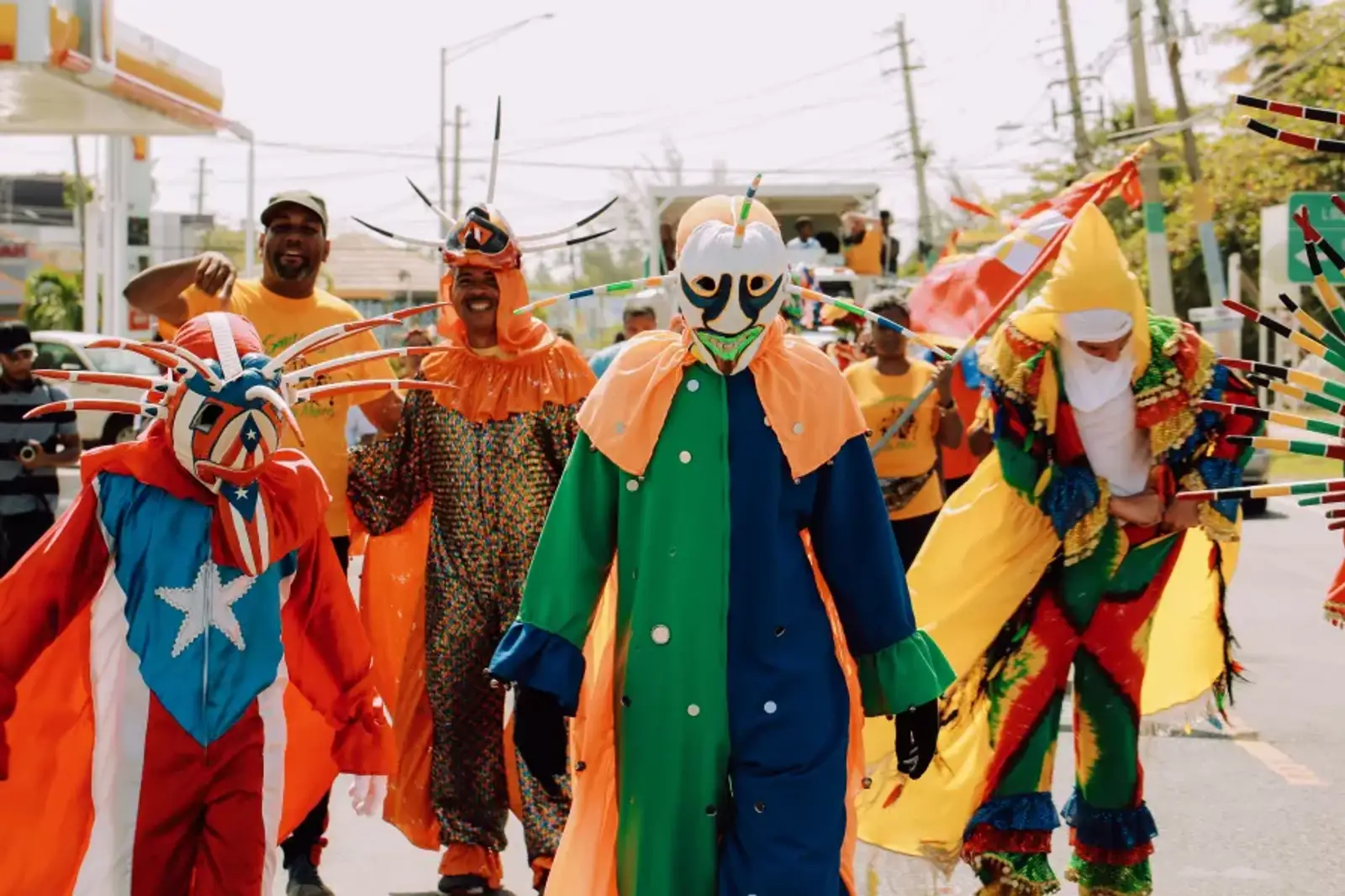 A colorful group of people dressed in the tradional attire of Puerto Rican vejigantes, which includes colorful masks.