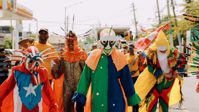 A colorful group of people dressed in the tradional attire of Puerto Rican vejigantes, which includes colorful masks.