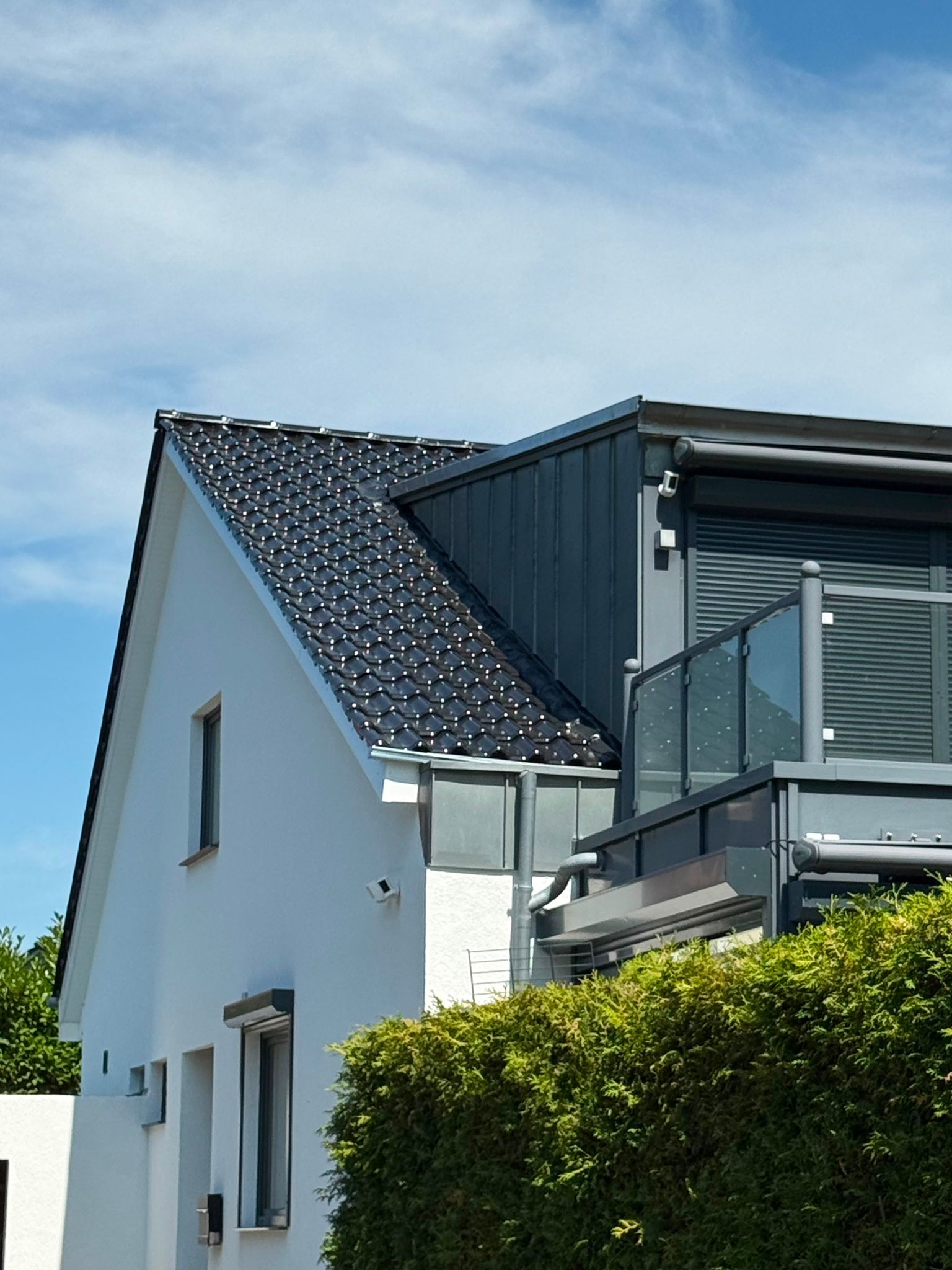 Weißes Giebelhaus in Bremen-Oberneuland mit Anthrazit-Steildach und metallverkleidetem Anbau