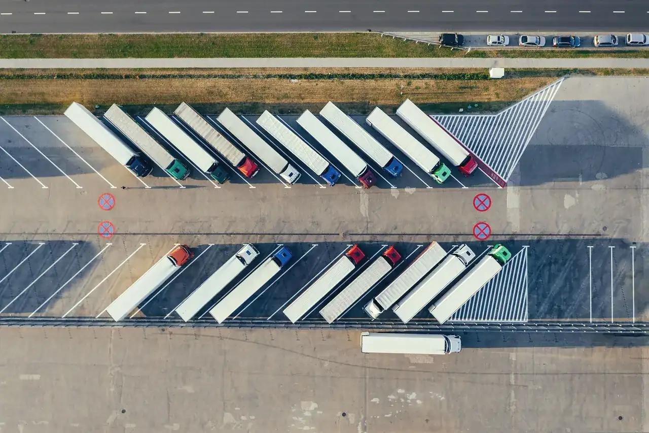 Rows of lorries with white trailers parked in a yard, seen from above