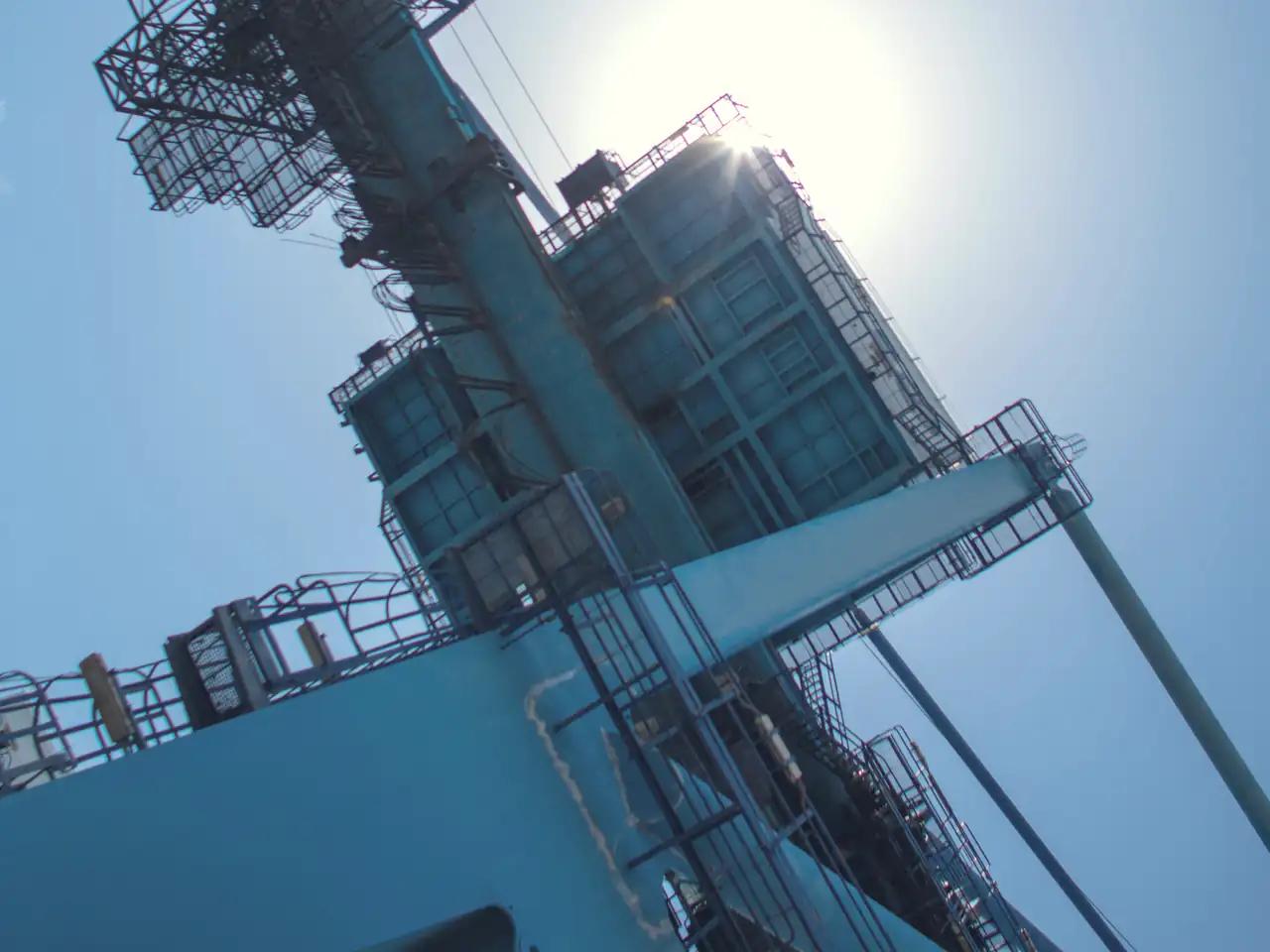 A quay crane at the Port of Mombasa seen from below, the sun behind its machinery house