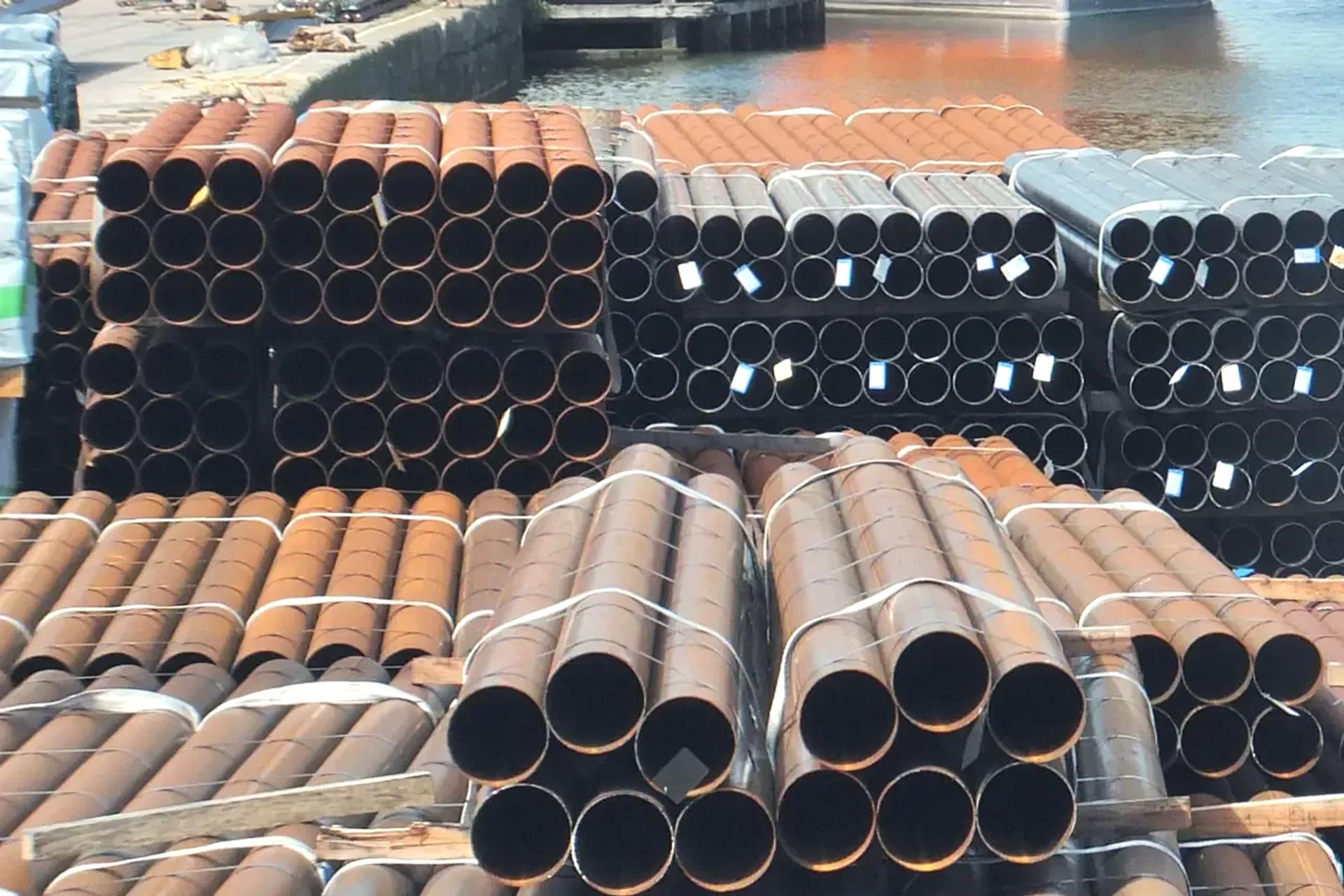 Bundles of steel pipes stacked on a quayside