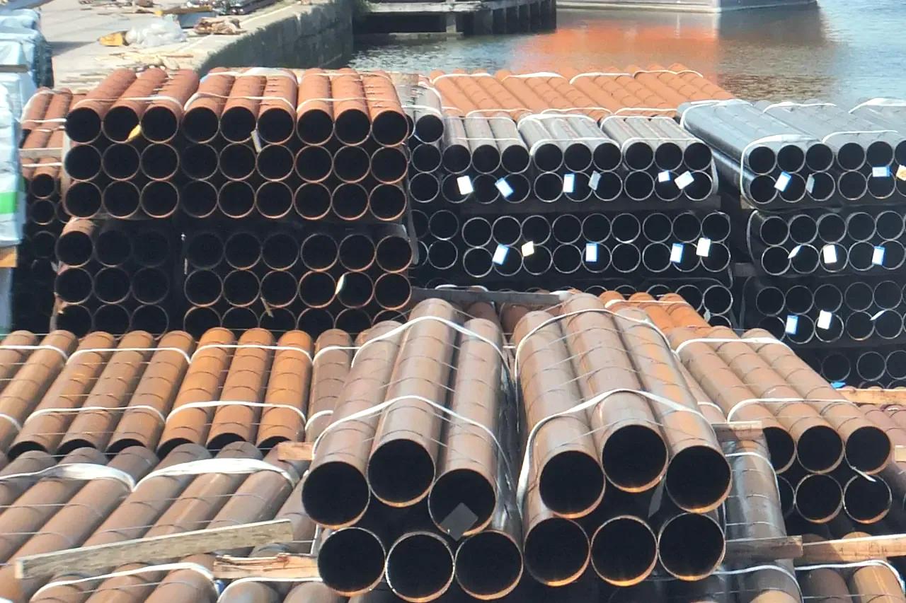 Bundles of steel pipes stacked on a quayside