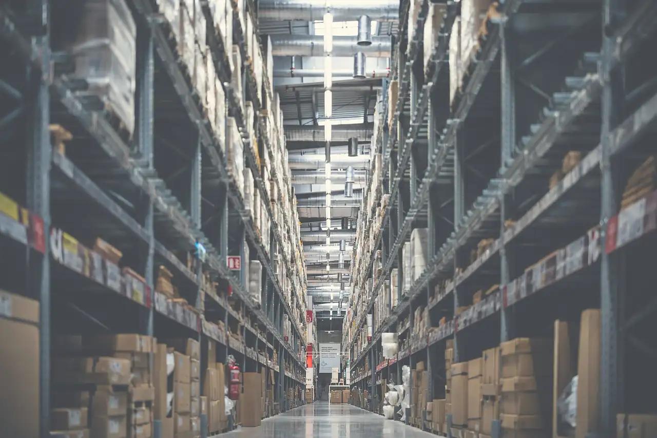 A tall warehouse aisle of racking stacked with cartons