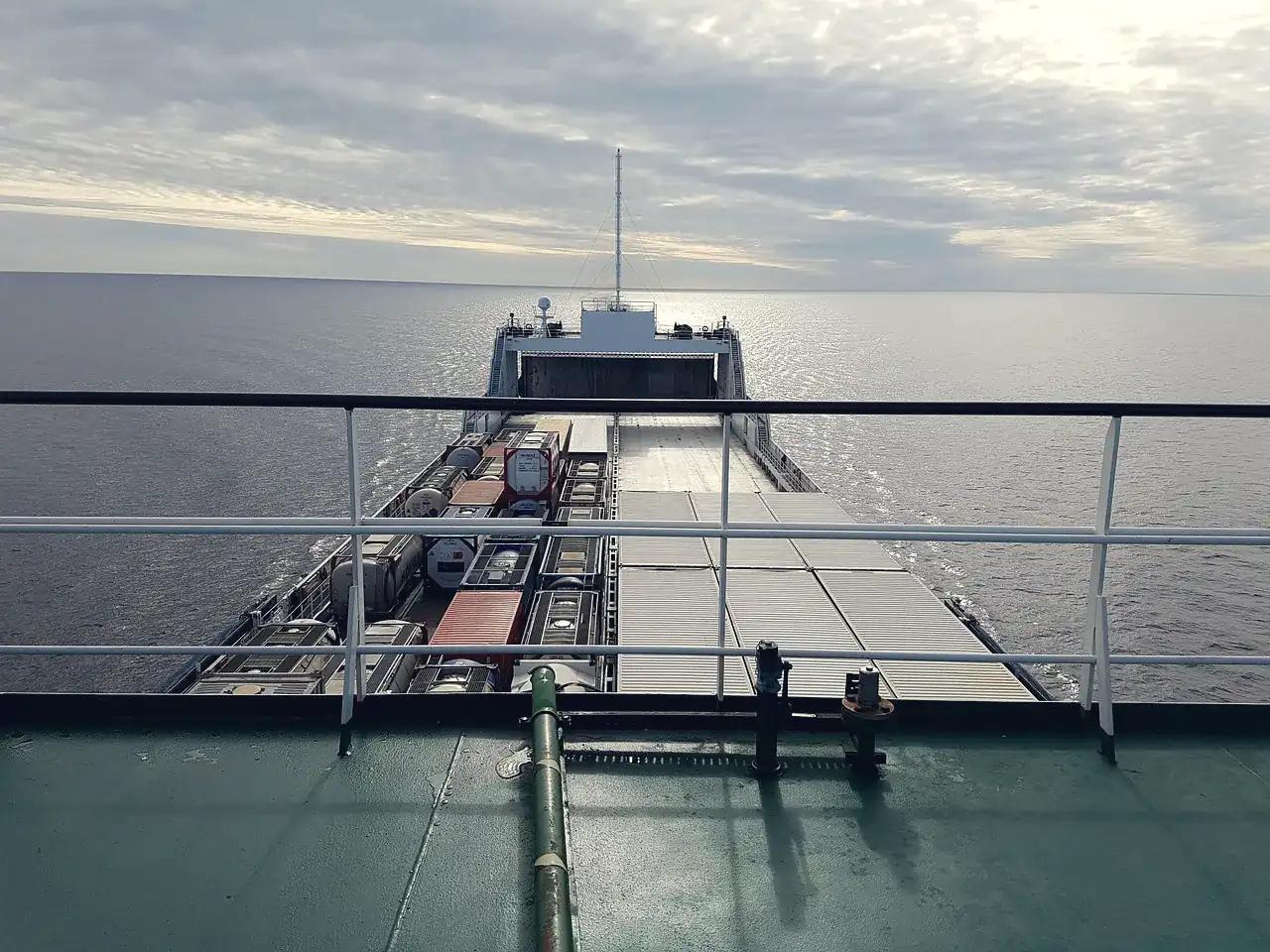 Containers stacked on a ship's deck, seen from the bridge, with grey sea ahead