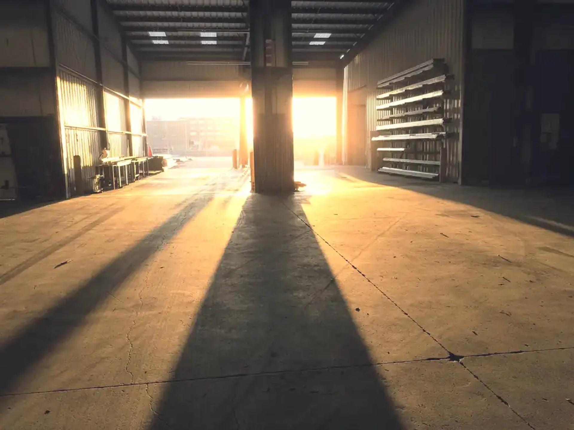 An empty warehouse with low sunlight coming through an open loading door