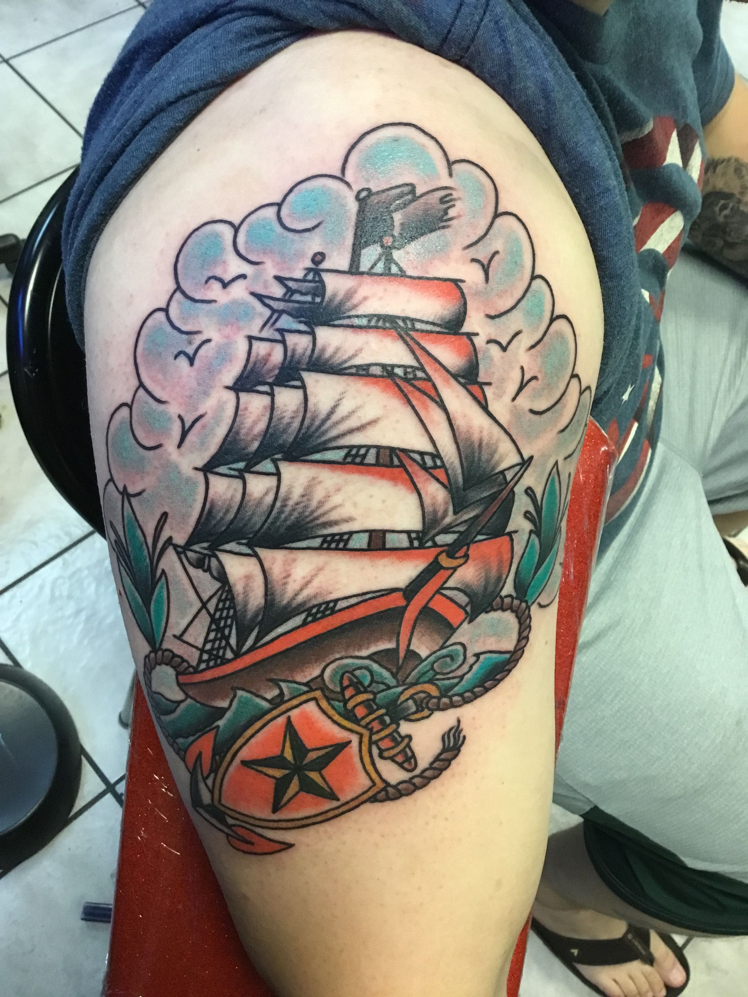 Traditional sailing ship tattoo on upper arm with bold colors.