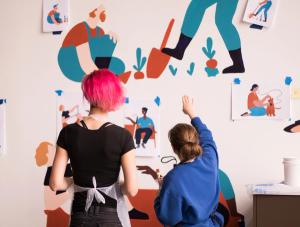 two gusto employees painting a mural in the gusto office