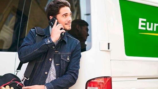 Mand taler i telefon foran Europcar varevogn